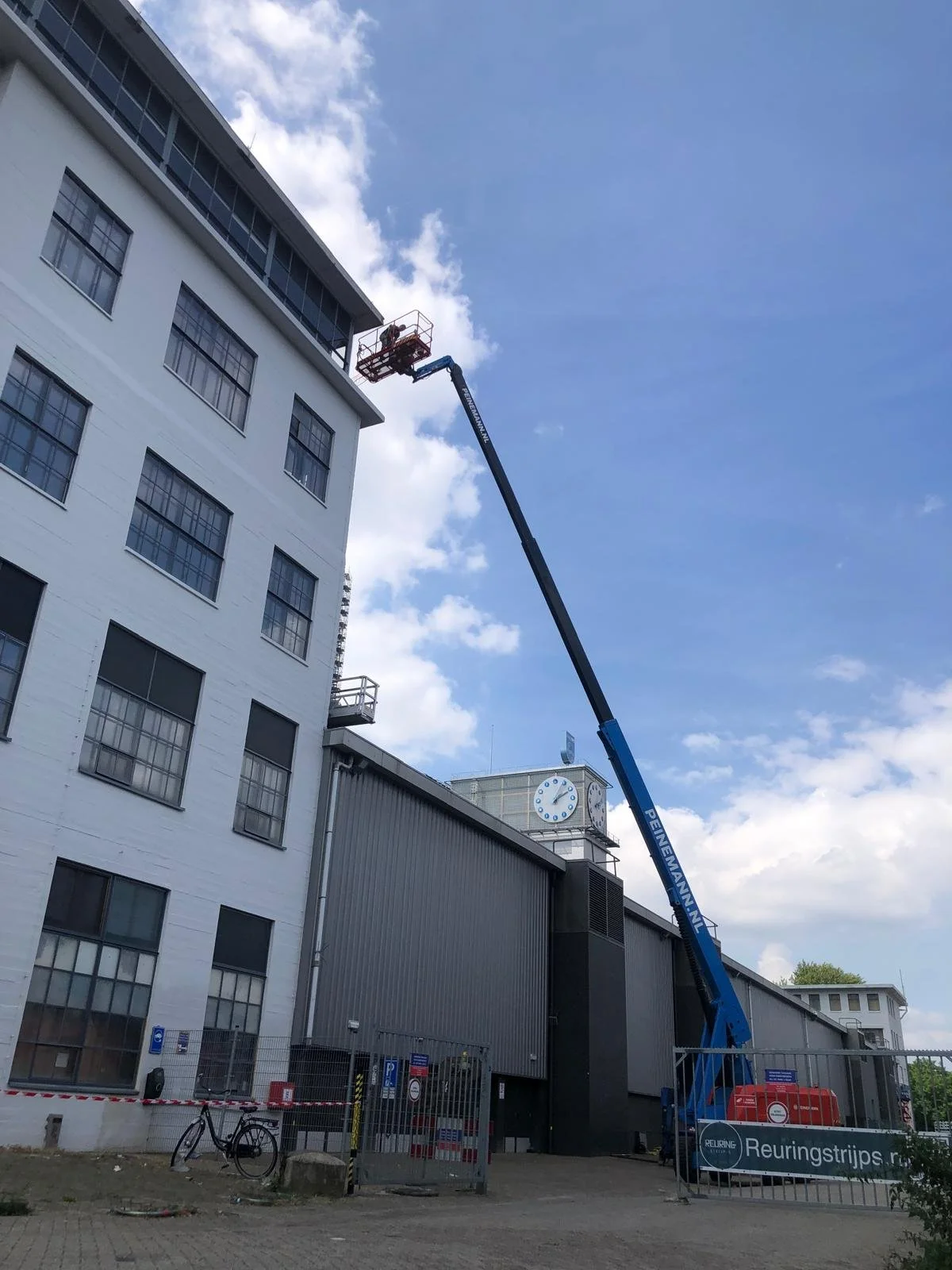 Betonreparatie met hoogwerker bij een industrieel gebouw.