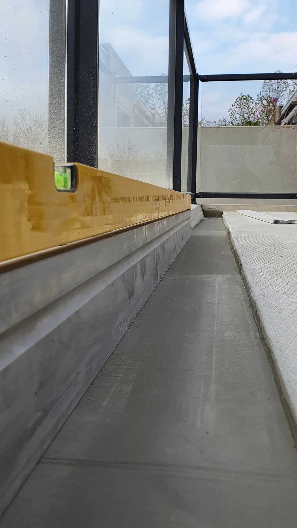 Betonreparatie en afwerking van een prefab balkonvloer bij een raamkozijn