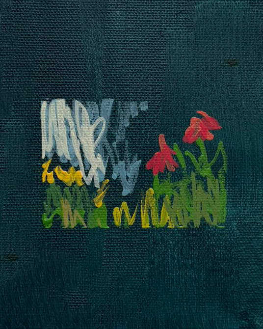 A small fabric patch with embroidered white, yellow, green, and red threads forming a decorative design on a dark textured background.