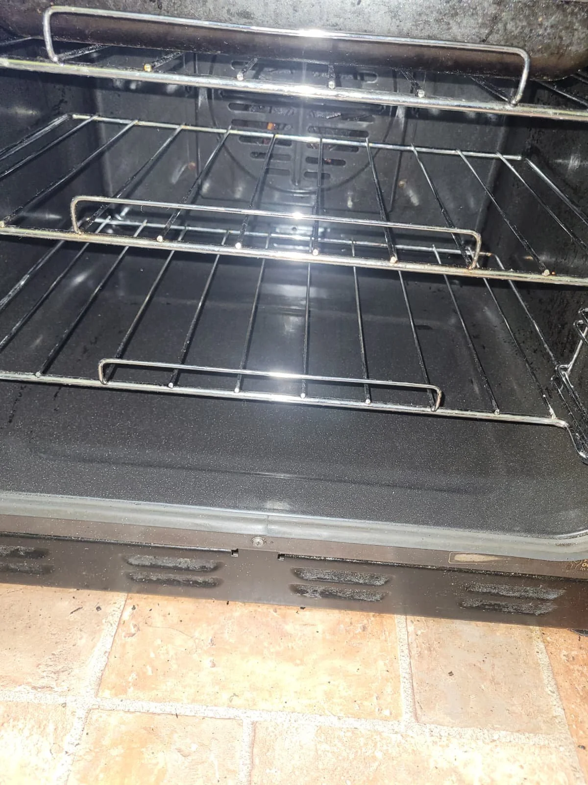 Empty black oven with metal racks installed, viewed from front.