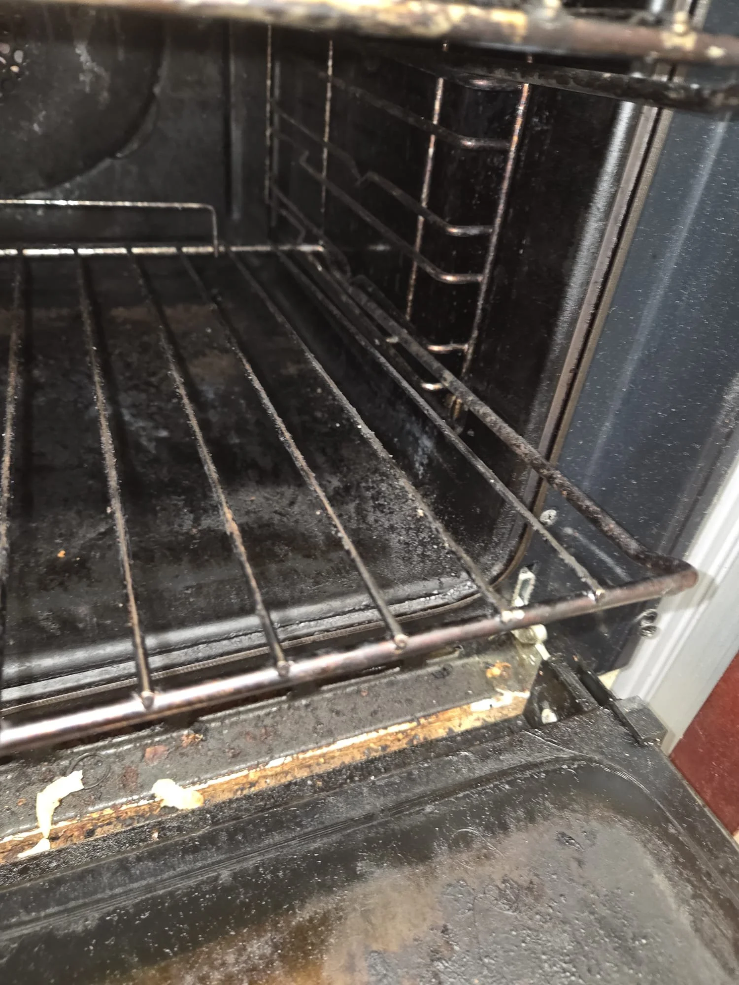 Inside a dirty oven with food debris and grease buildup on the oven racks, floor, and sides.