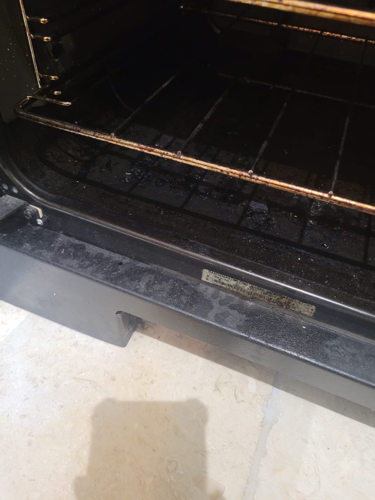 Empty oven with burnt residue on the bottom rack.