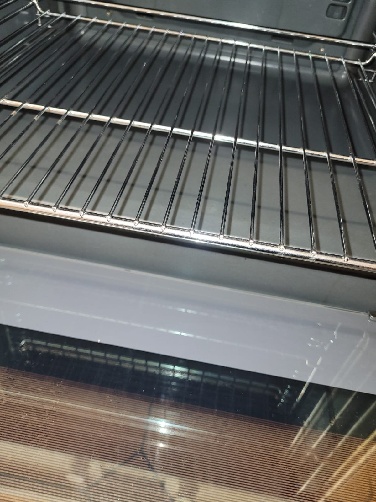 The image shows the inside of an oven with a metal wire baking rack in the oven rack slots.