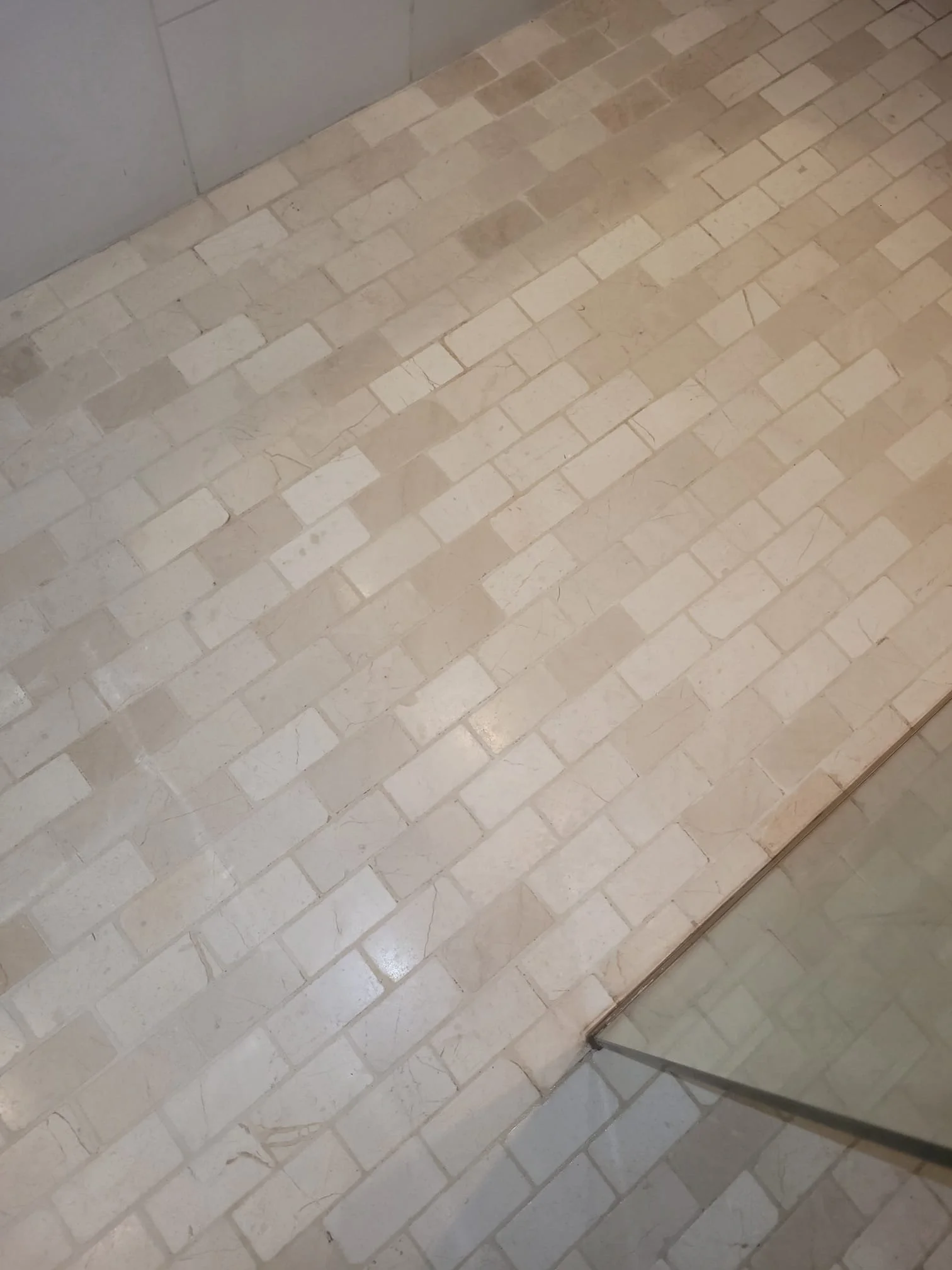 Close-up of beige and cream brick flooring next to a glass door.