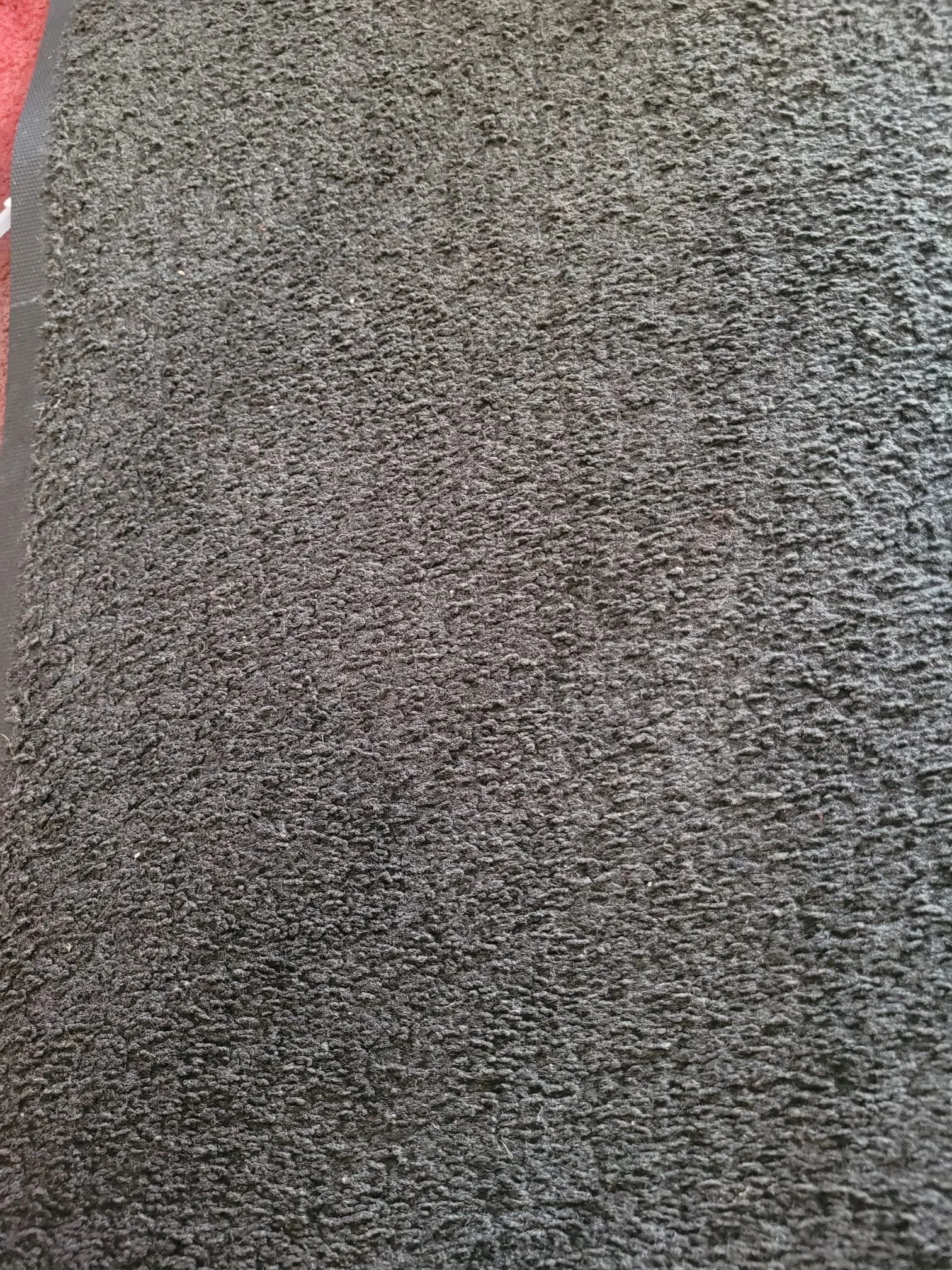Close-up view of a textured dark grey surface, possibly a rubber mat or asphalt.