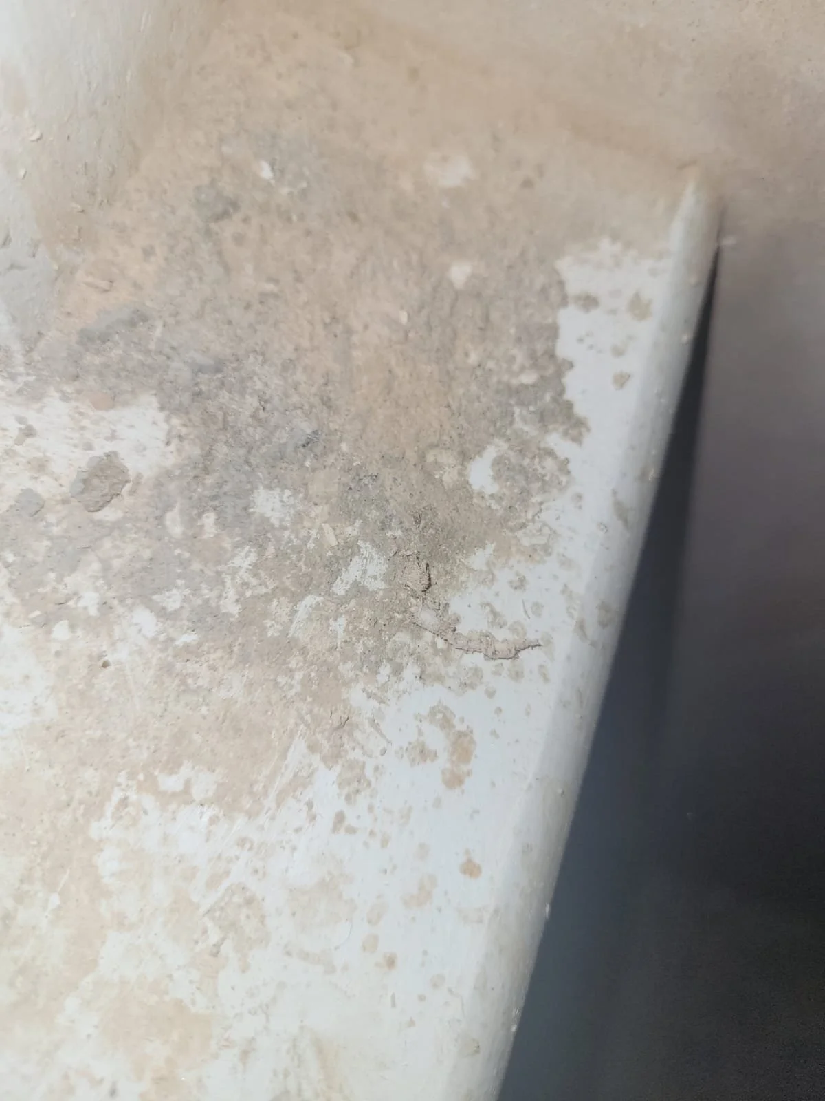 Close-up of a dirty, stained wall with peeling paint and a crack, showing signs of wear and damage.