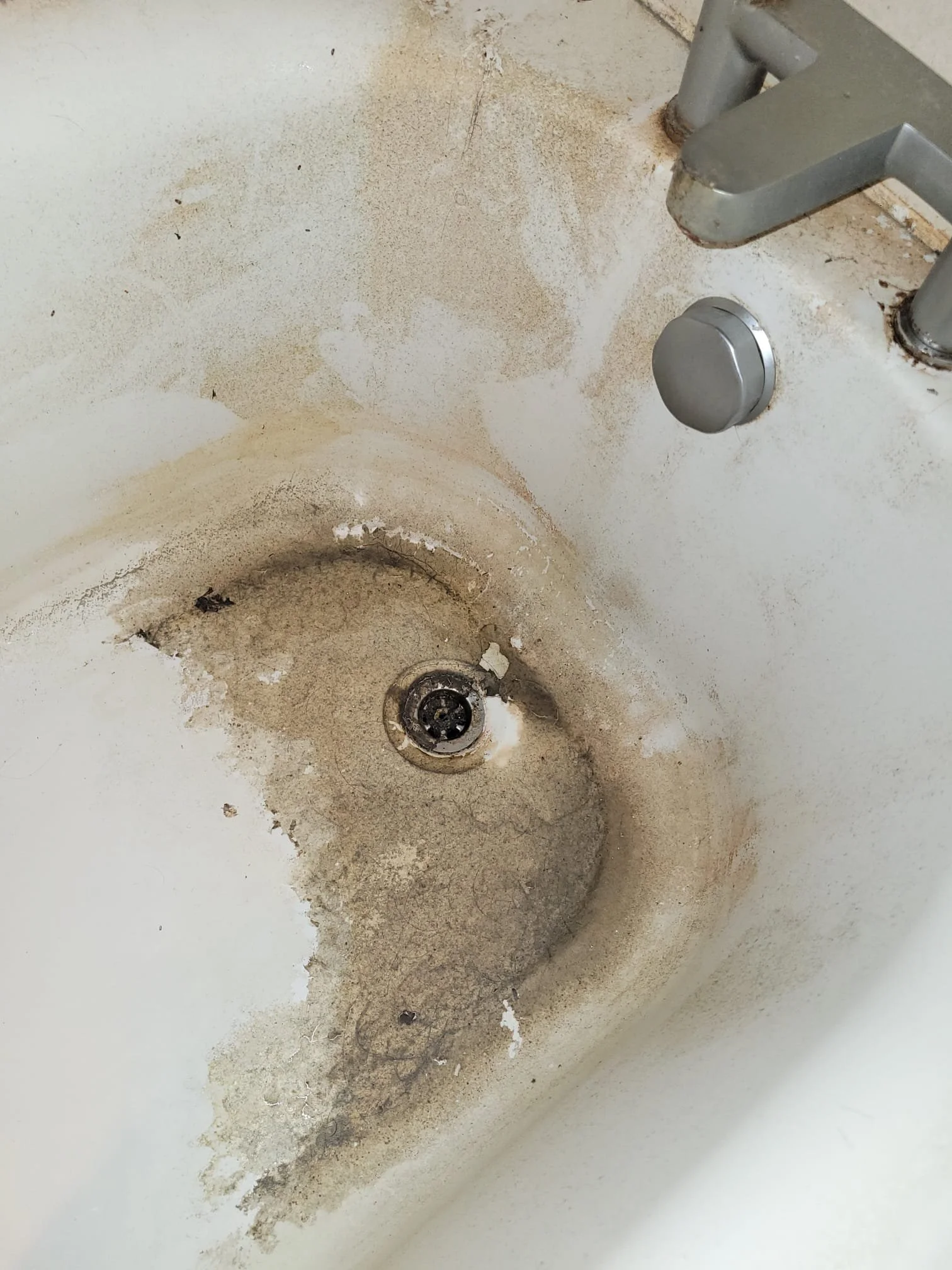 Dirty bathroom sink with grime, dirt, and stains around the drain and on the surface.
