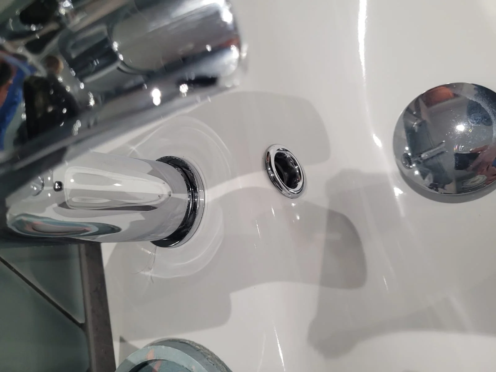 Close-up of a bathroom sink faucet with a shiny chrome finish and a separate hot and cold water knob.