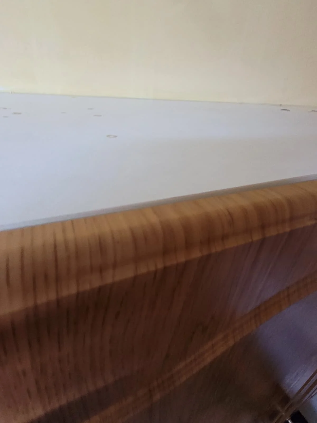 Close-up of a wooden bed frame with a white mattress on top.
