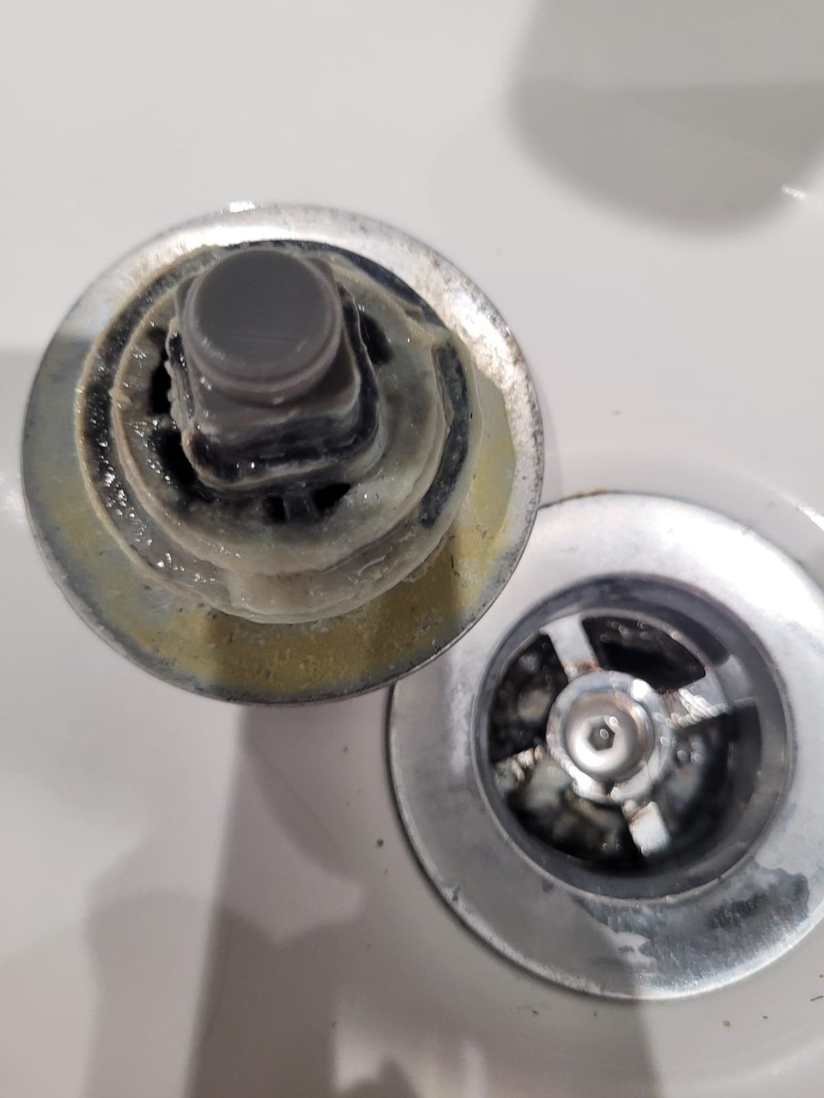 Close-up of a toothbrush holder with a black toothbrush in a bathroom sink.