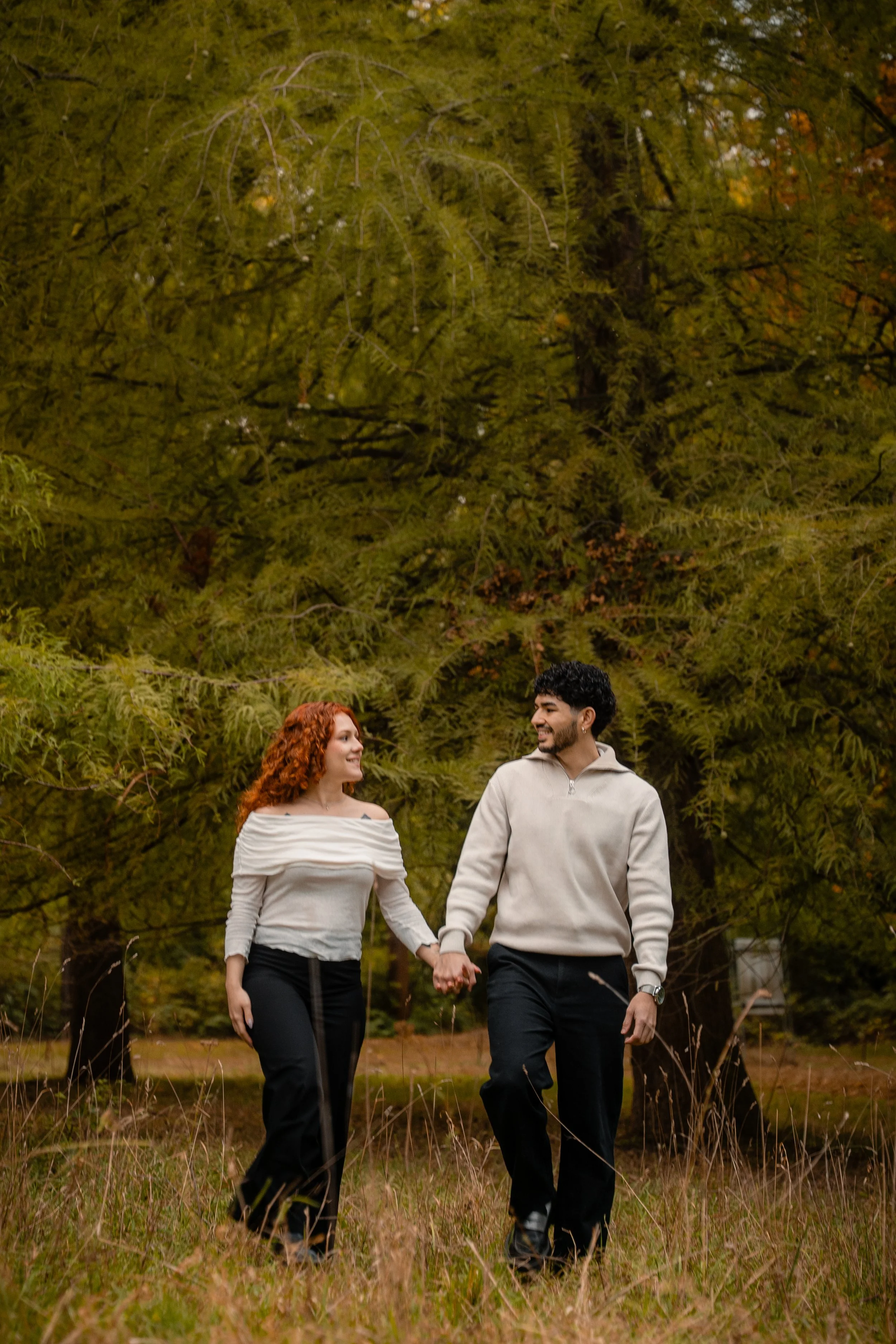 A couple walking hand in hand outdoors in a forested area during fall. Couple photography