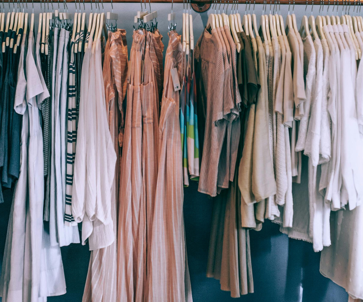 Rõivad, mis ripuvad poeriiulil – erinevad neutraalsetes toonides ja triibulised pluusid ning püksid.