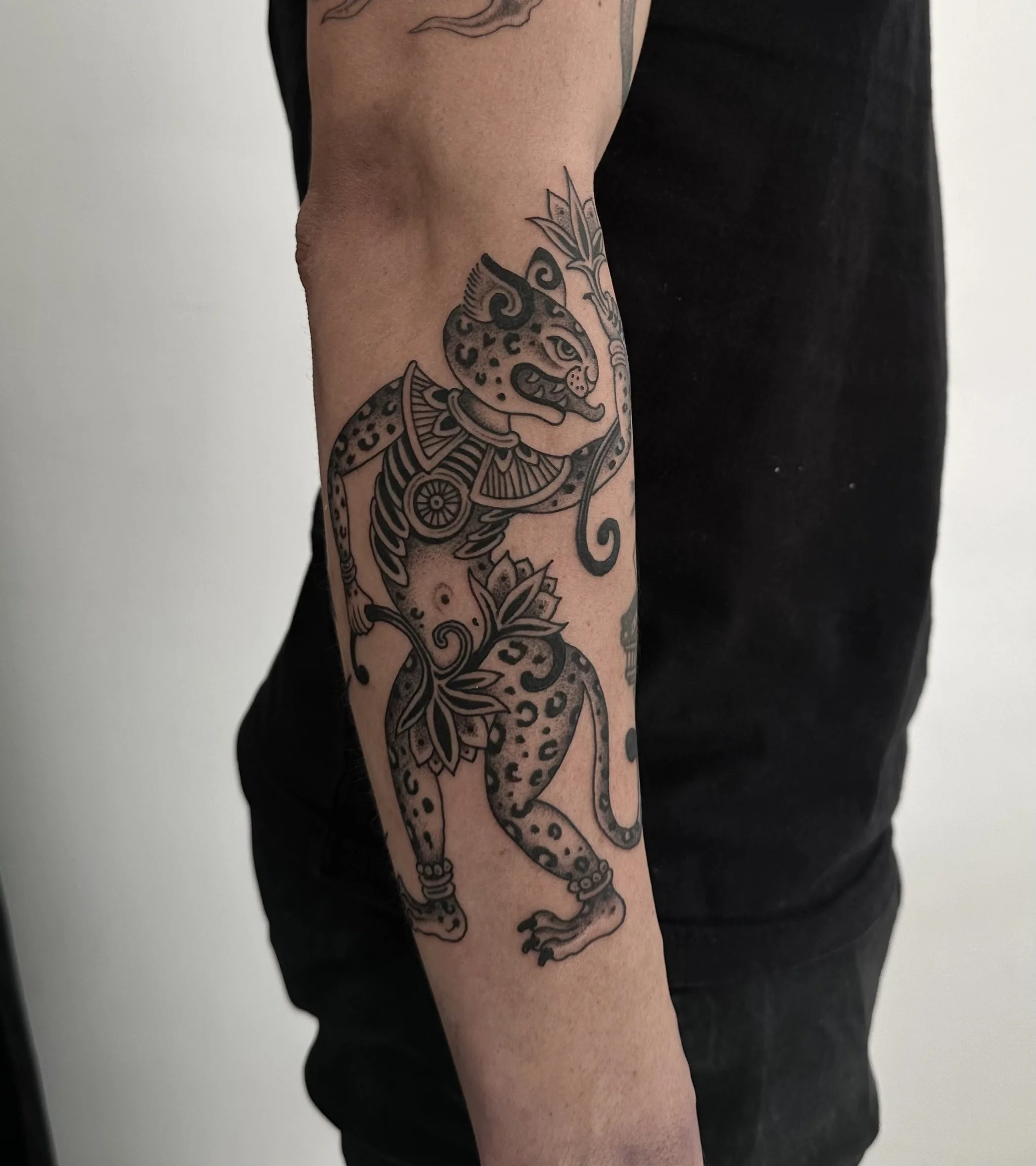 Tattoo of a stylized wildcat with a floral pattern on the arm.