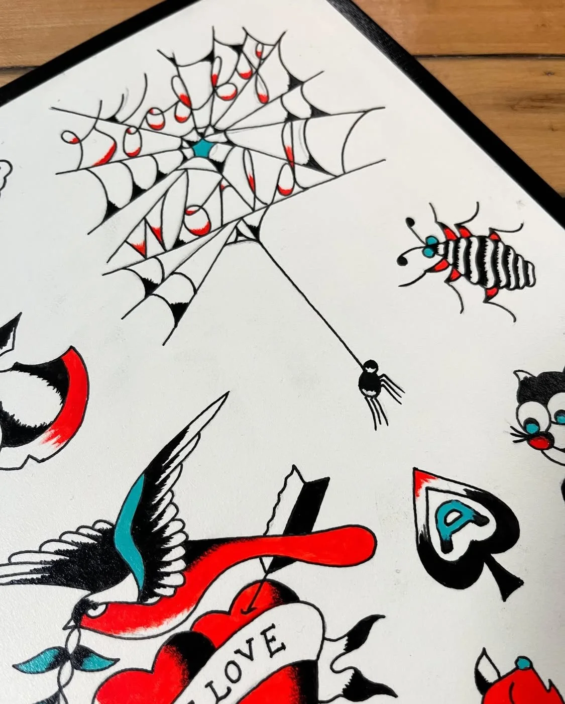 Tattoo-style drawing of a spider web, a bird, a bee, a cat, and various symbols with bold black, red, and blue colors.