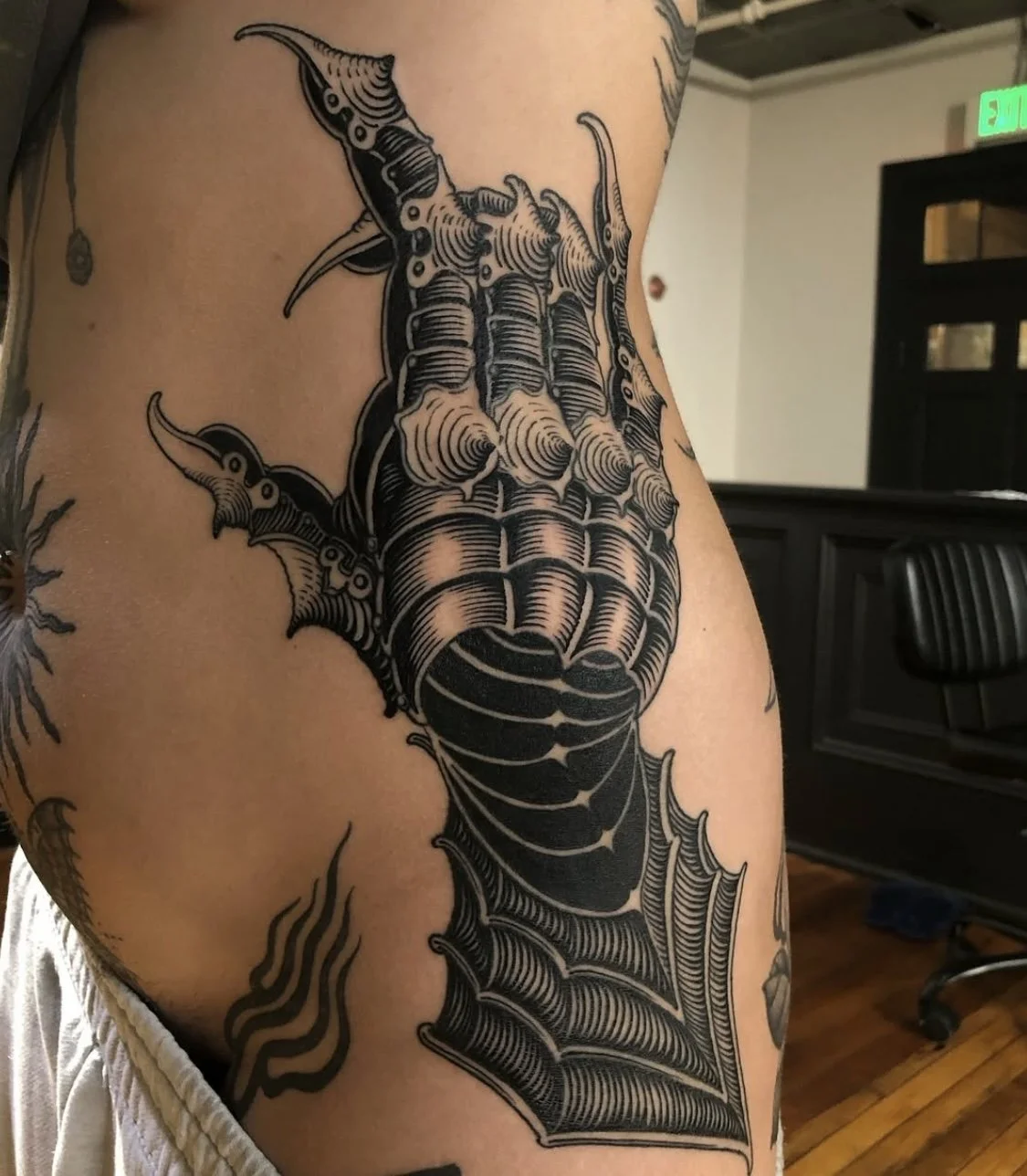 Tattoo of a stingray with a web design at the bottom, inked in black on a person's upper arm.