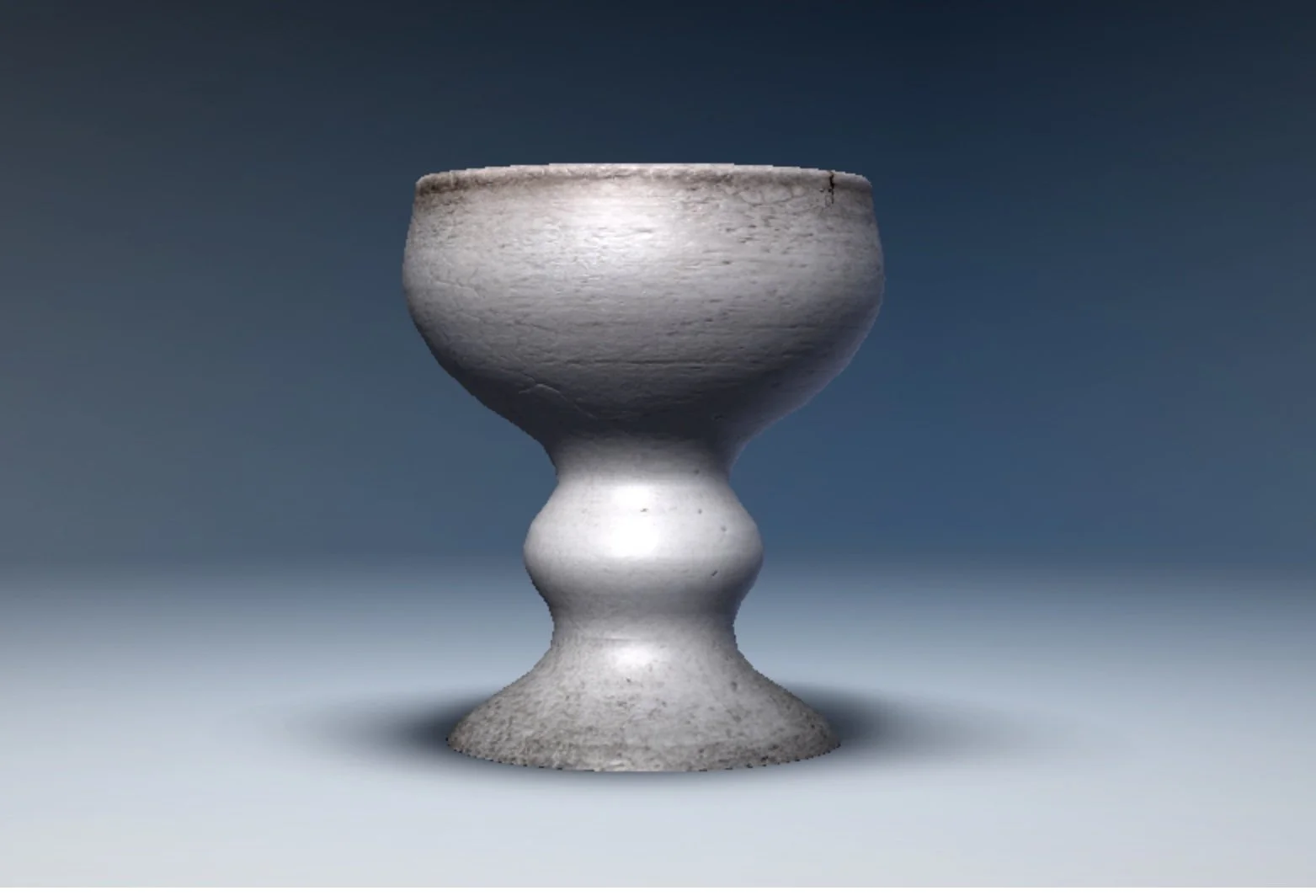 A metallic goblet with a textured, shiny surface, set against a cloudy sky background.