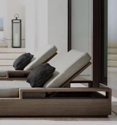 Two adjustable lounge chairs with gray cushions and dark pillows inside a modern indoor space.