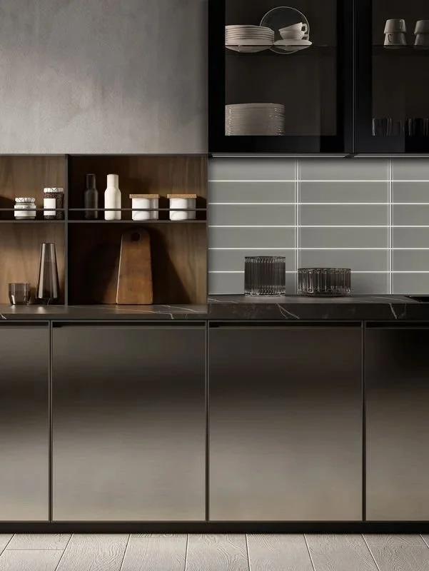 Modern kitchen with black and gray cabinets, open shelving with dishes, glasses, and decorative items, gray subway tile backsplash, and wooden accents.
