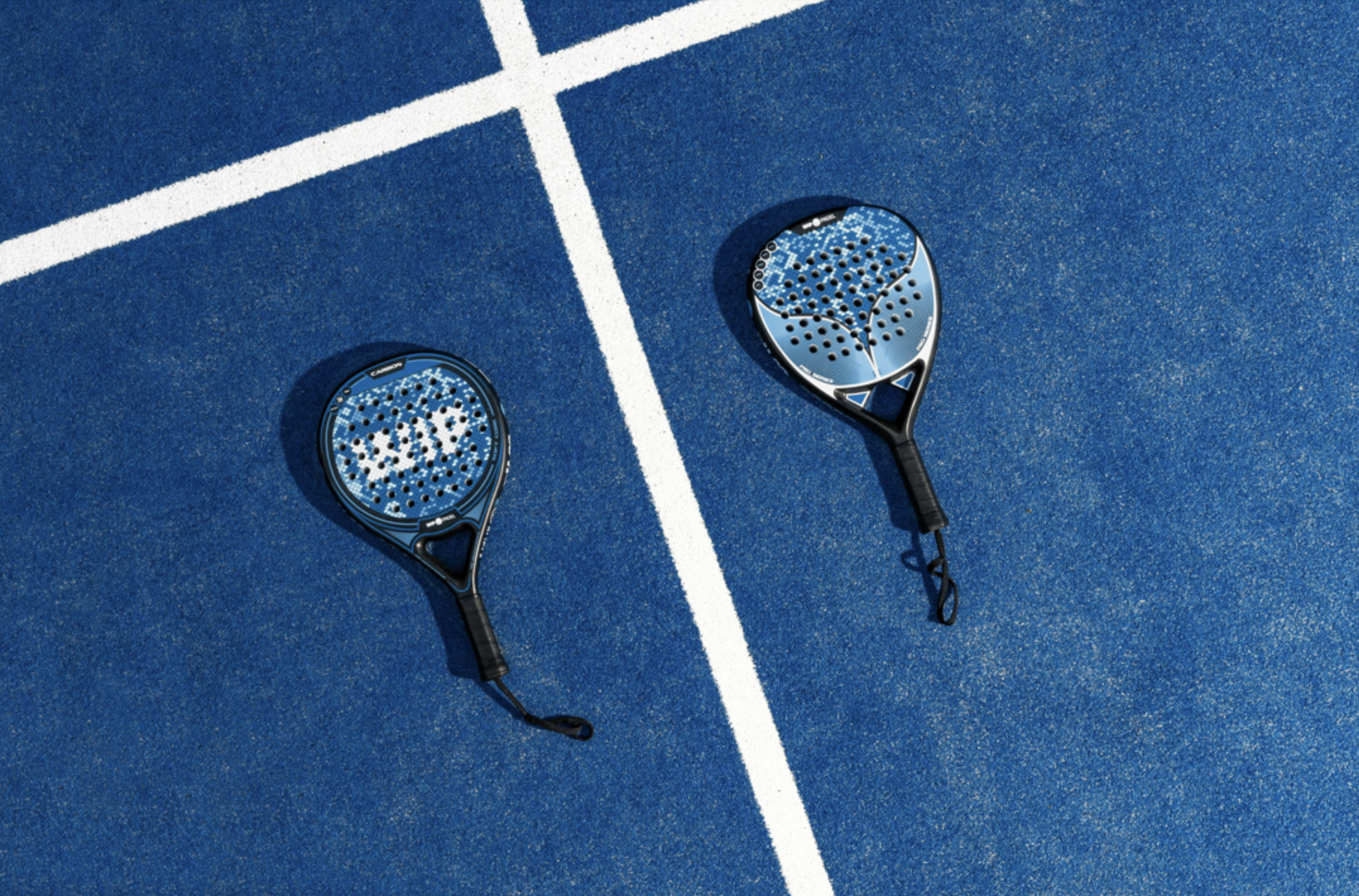Two tennis rackets resting on a blue tennis court with white lines.