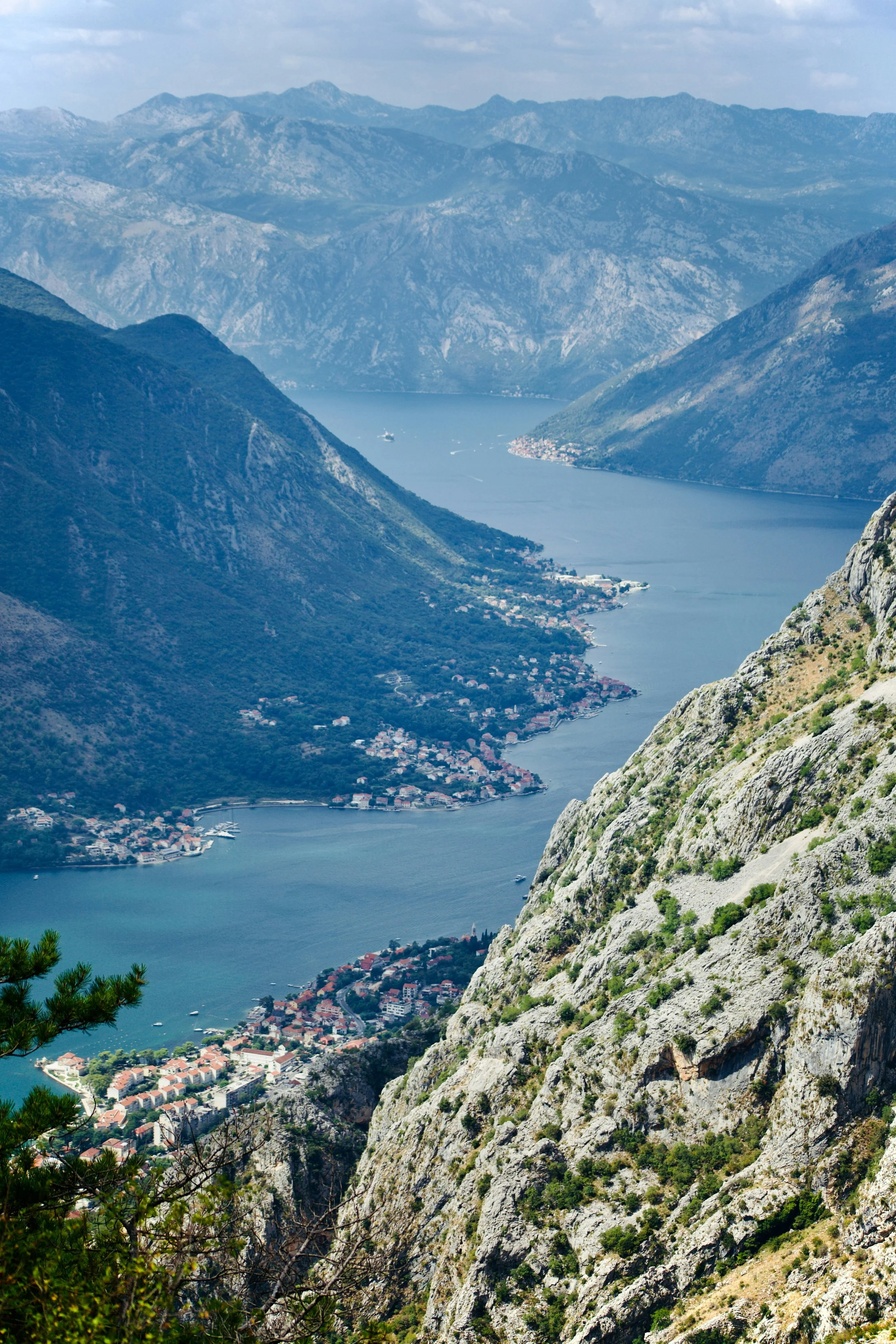 Scenic view of a fjord with surrounding mountains and a small town at the water's edge.