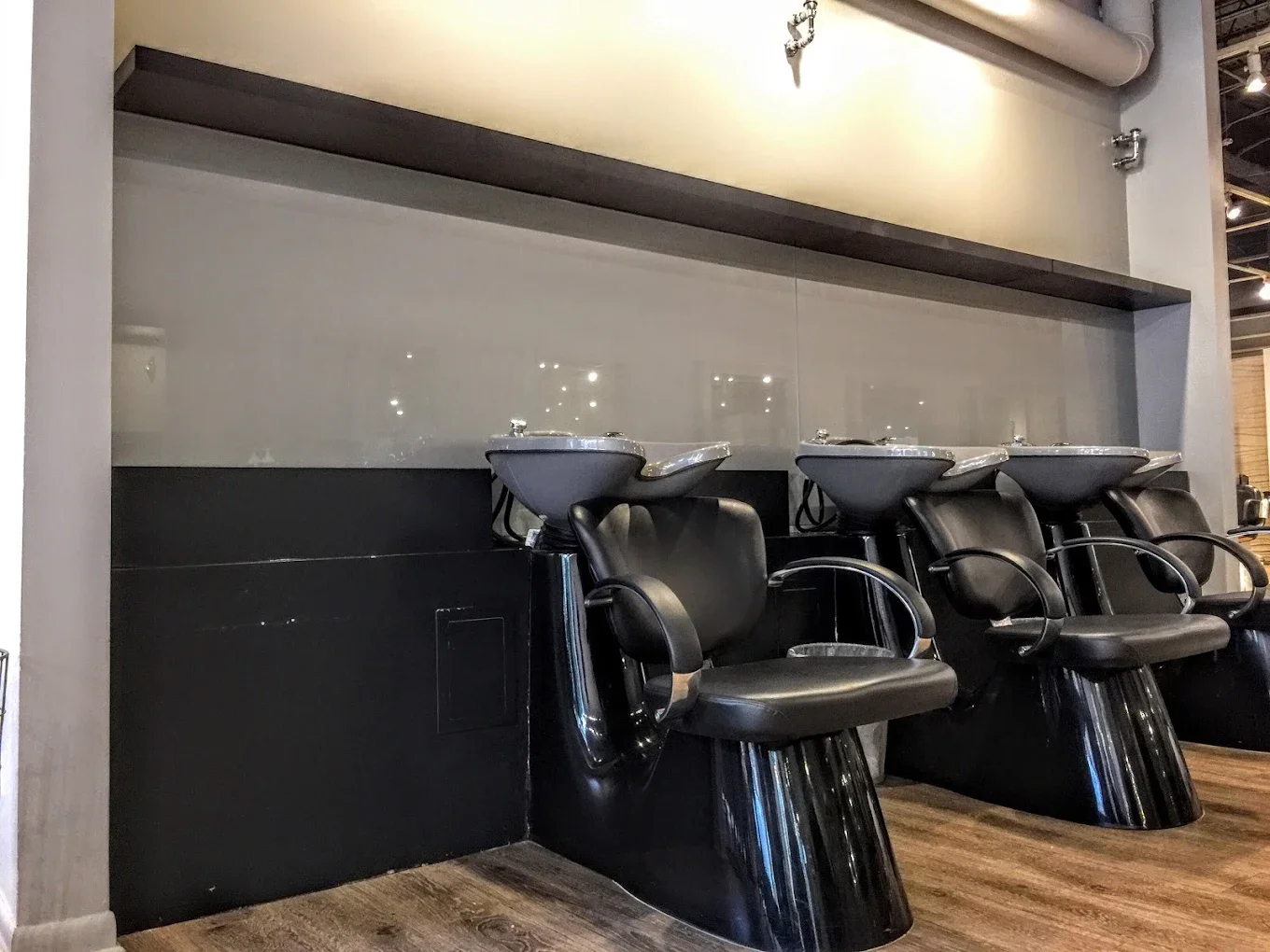 Three black salon chairs with washbasins in a modern hair salon.