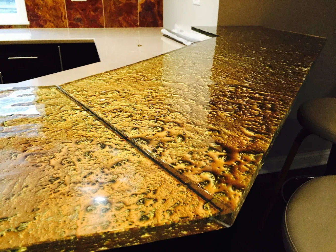 Close-up of a polished, speckled granite countertop with shades of gold, black, and brown in a kitchen or bar area.