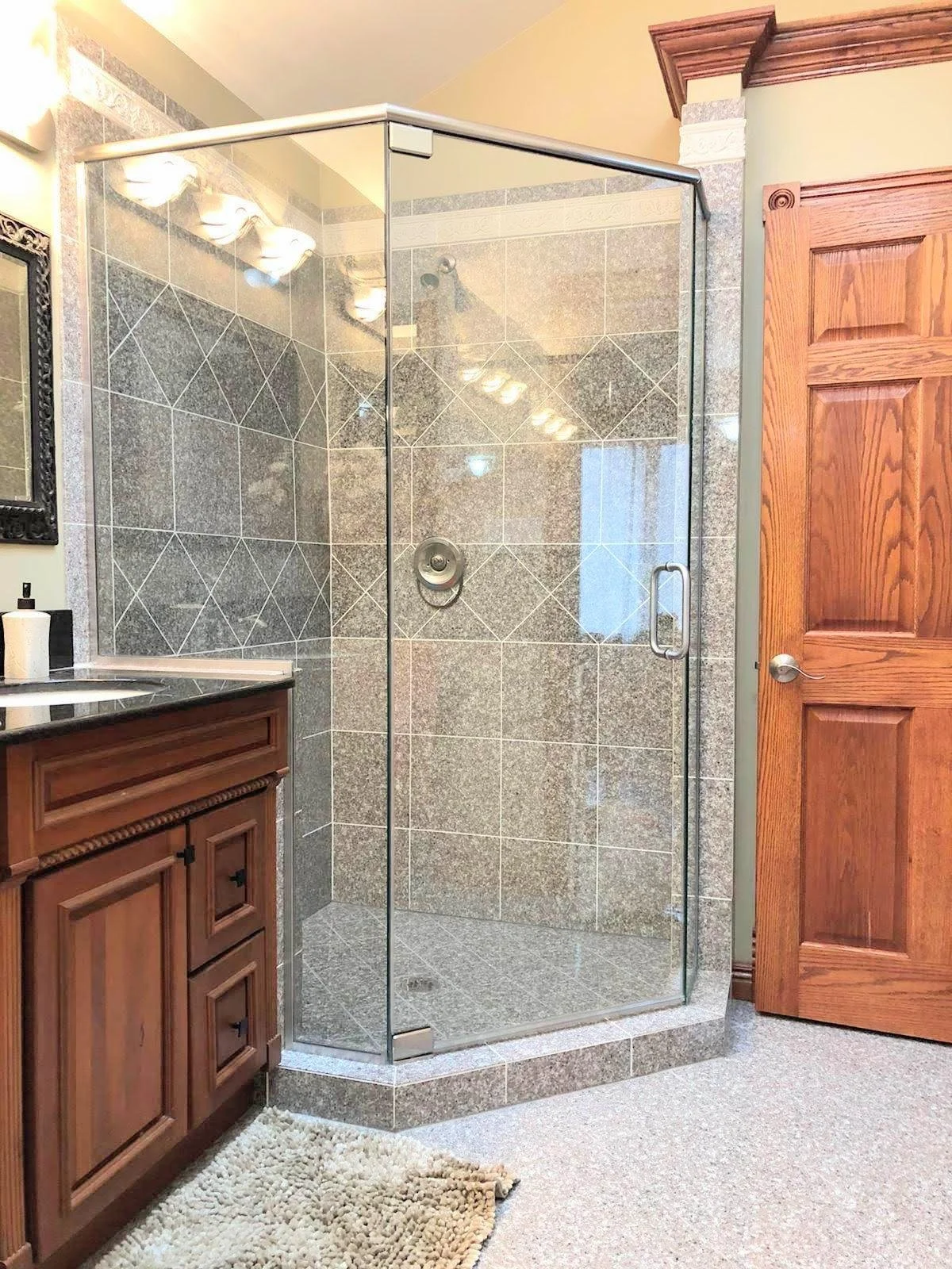 Bathroom with a glass shower enclosure, wooden cabinet, and a door.