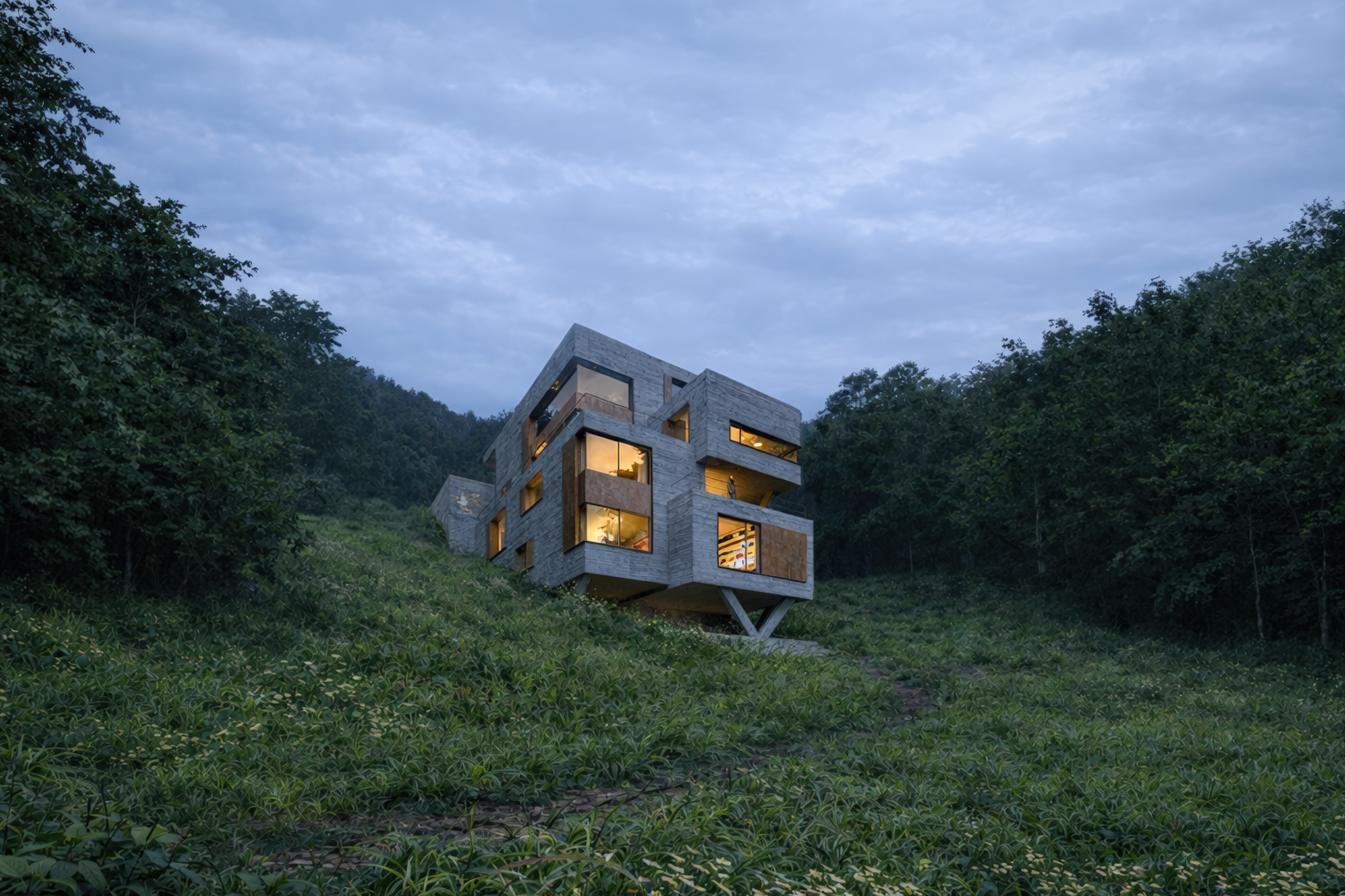 V-Stack Haus Heidelberg, von Henecka Architekten BDA, Modernes Haus auf einer steilen, bewachsenen Hügel mit Blick auf den Himmel bei Sonnenuntergang.