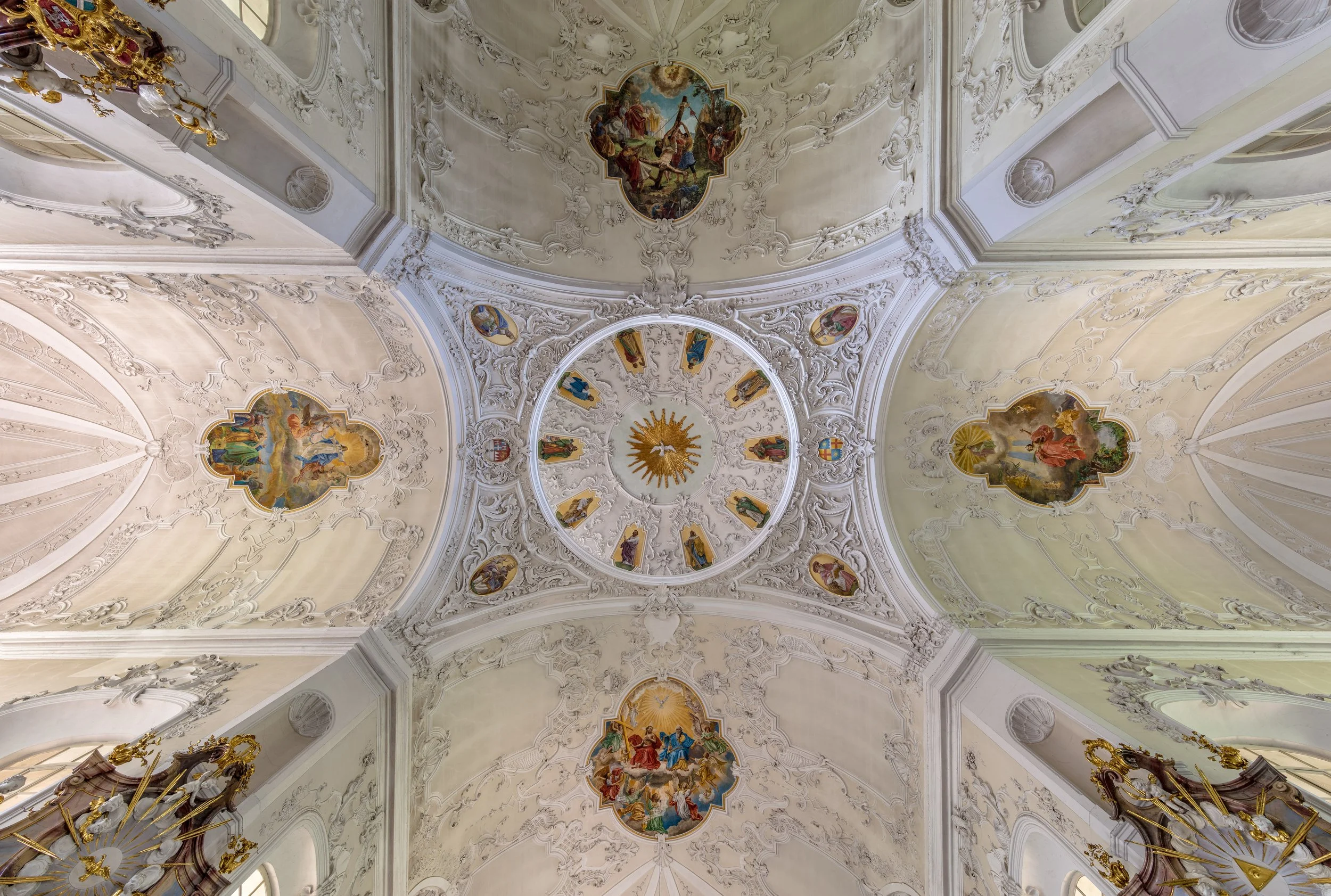 Deckengestaltung mit barocken Malereien und aufwändiger Stuckdekoration in einem prunkvollen Raum.