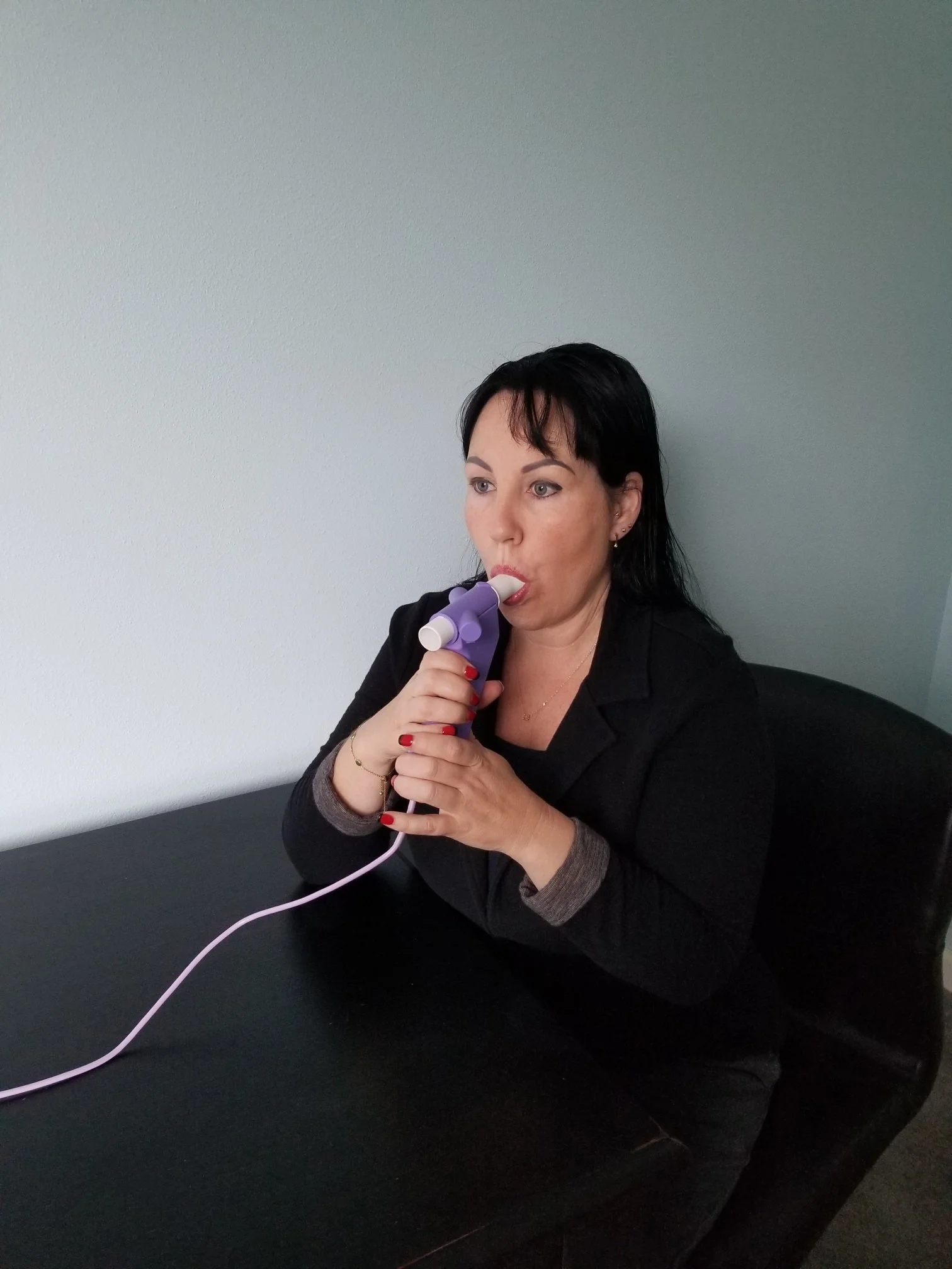 Employee performing OSHA-compliant spirometry test with a handheld purple breathing device during workplace health screening by Precision Mobile Testing.