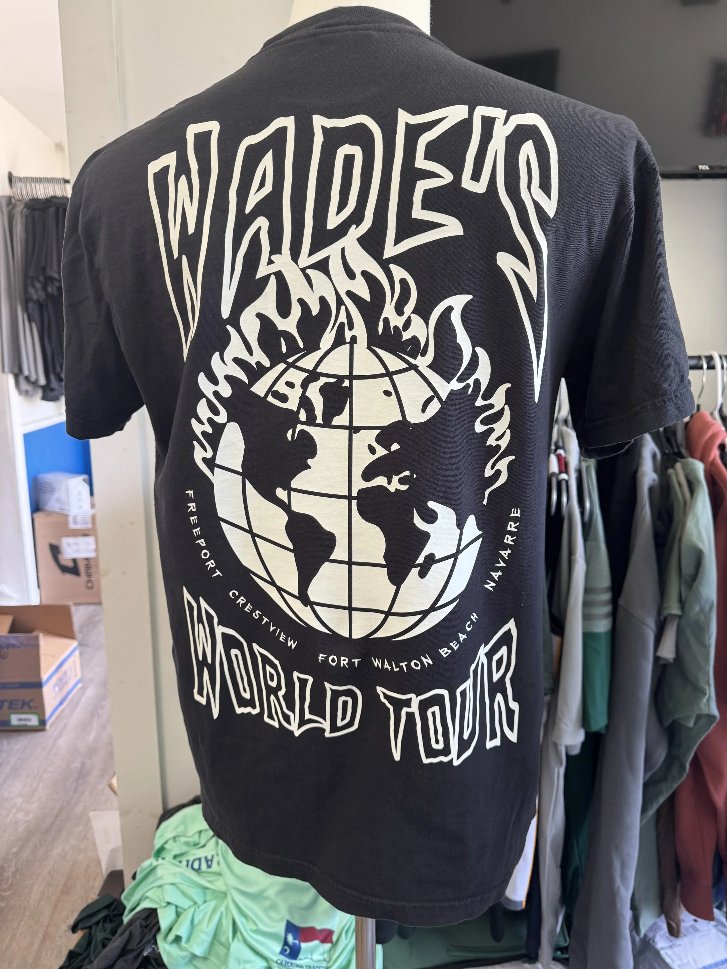 Black T-shirt featuring a graphic design with the words 'WILDERS WORLD TOUR' and a globe with flames, listing locations: Freeport, Crestview, Fort Walton Beach, Navarre.