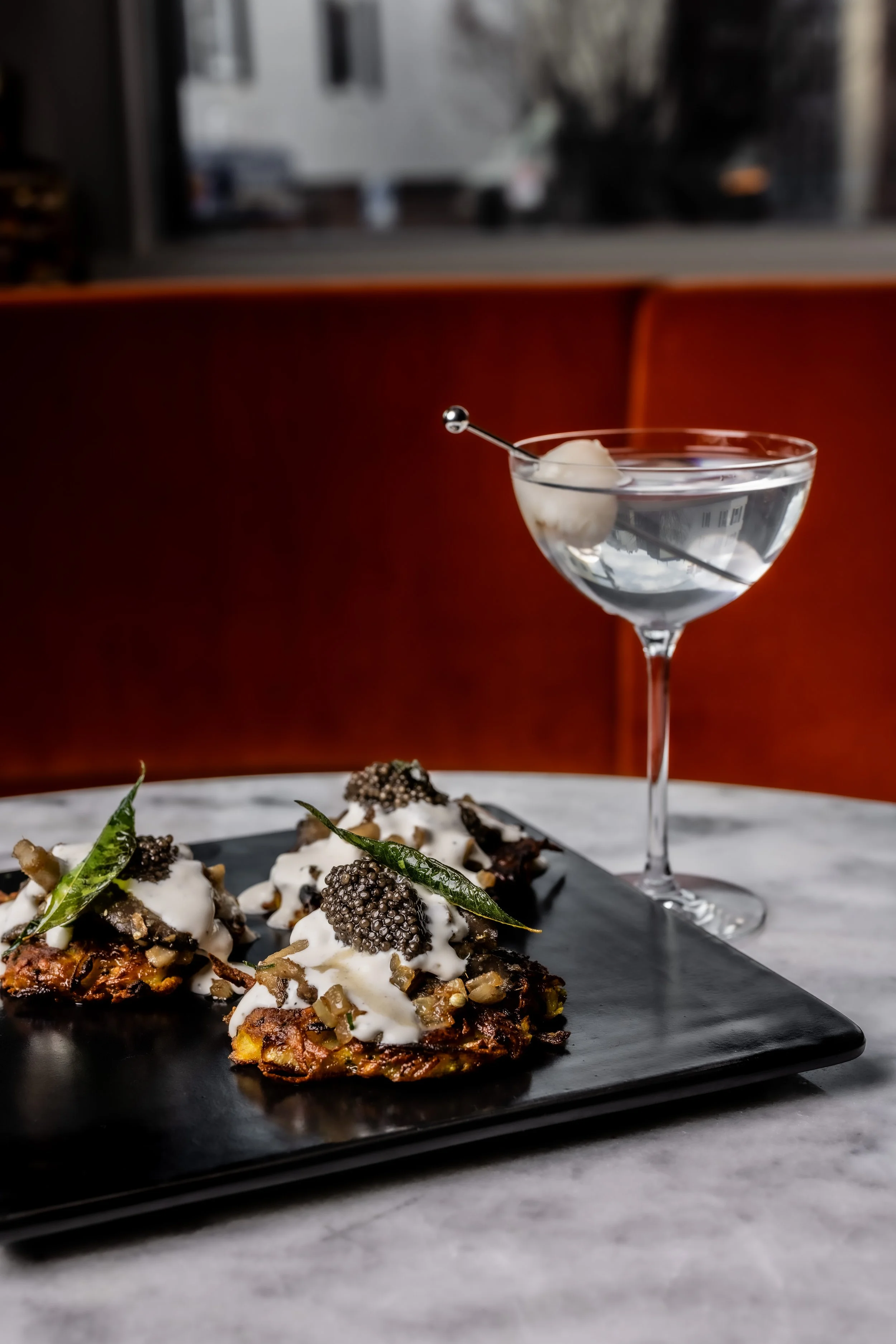 A photo of a martini and latkes with caviar