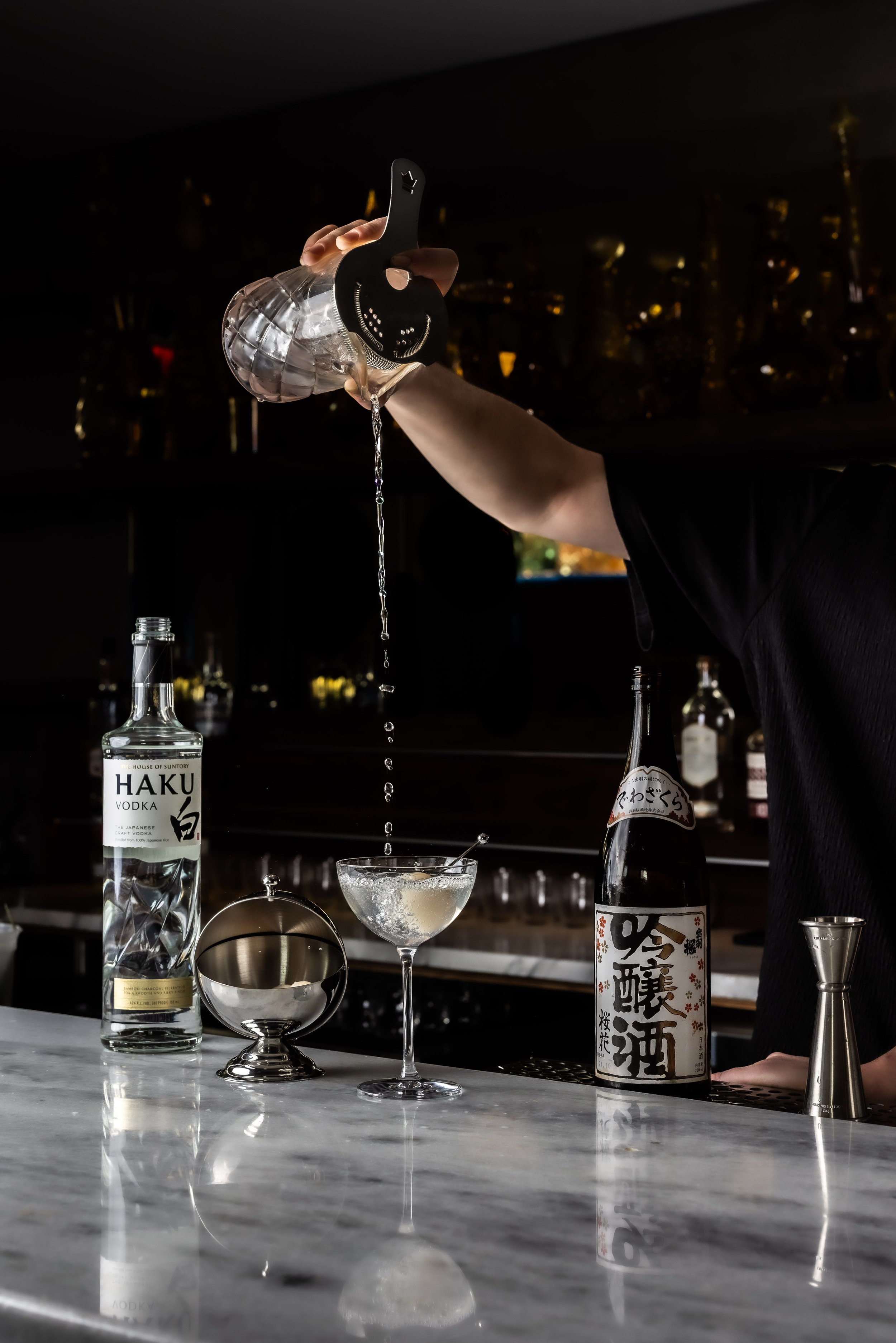 A bartender pouring a signature martini cocktail at FOLK Brooklyn
