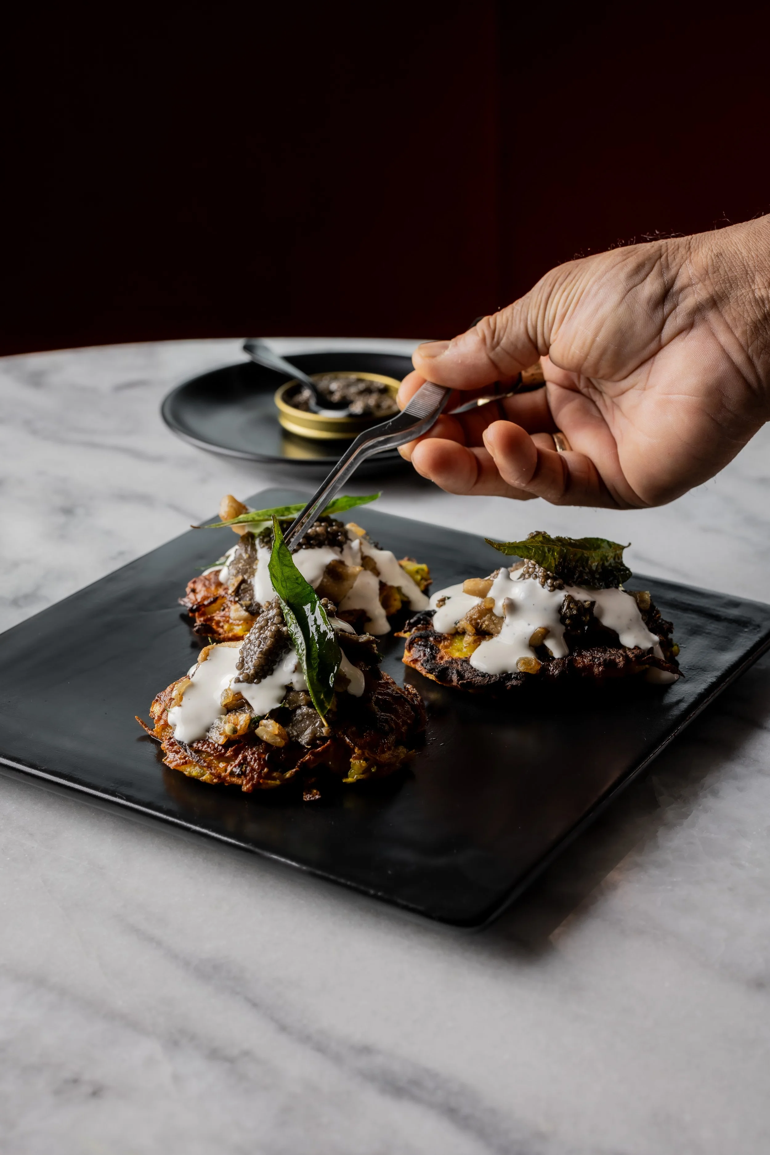 A chef plating caviar on latkes