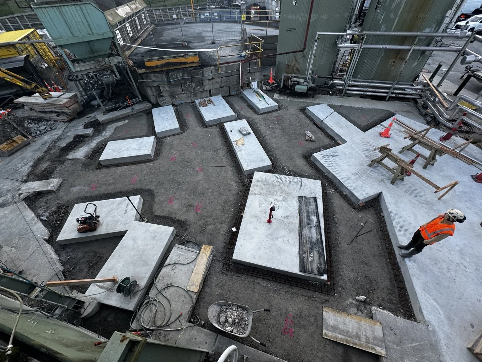 Construction worker in a safety vest installing concrete slabs at an industrial site