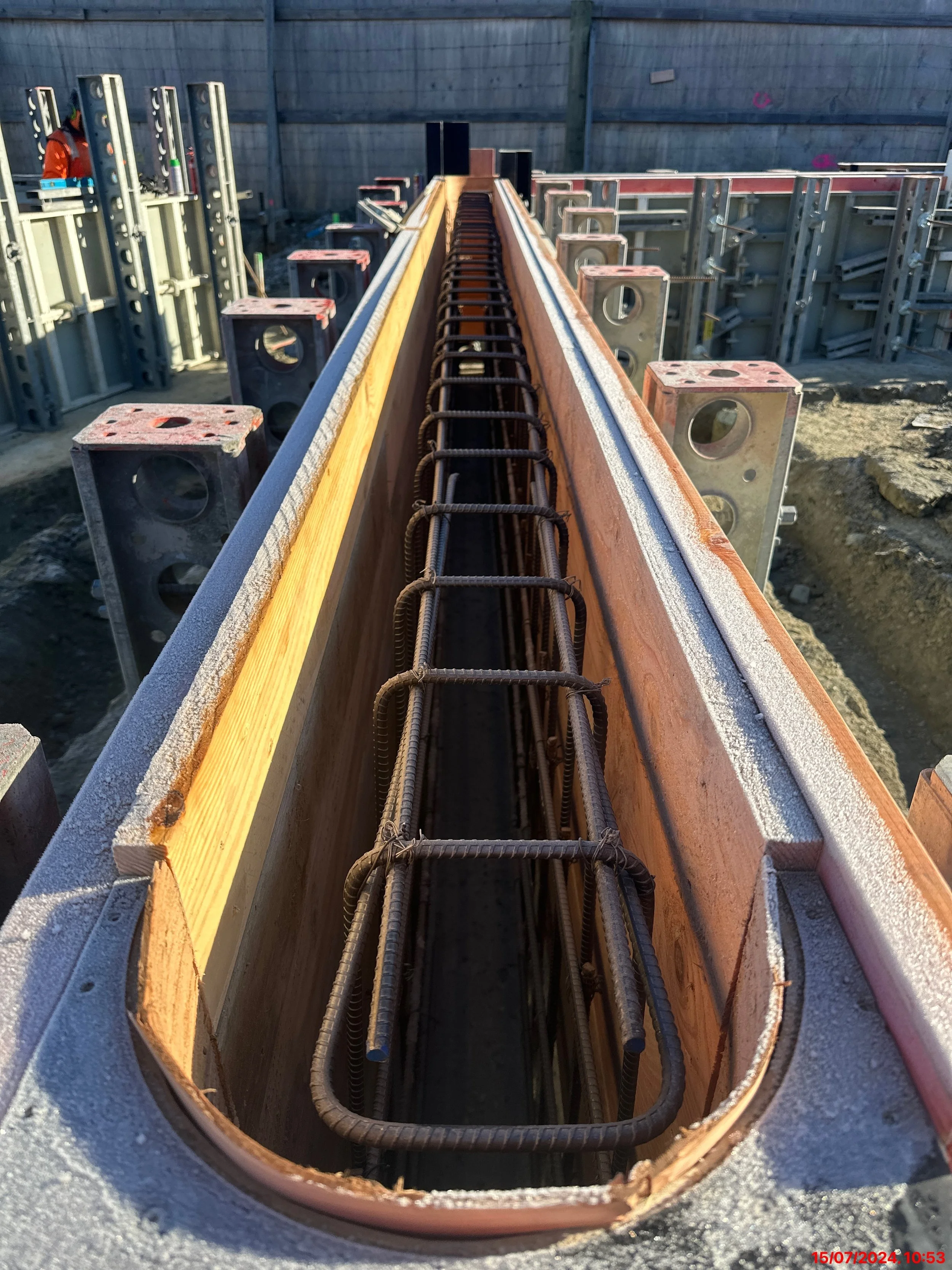 Close-up of a reinforced concrete beam form filled with rebar cages at a construction site