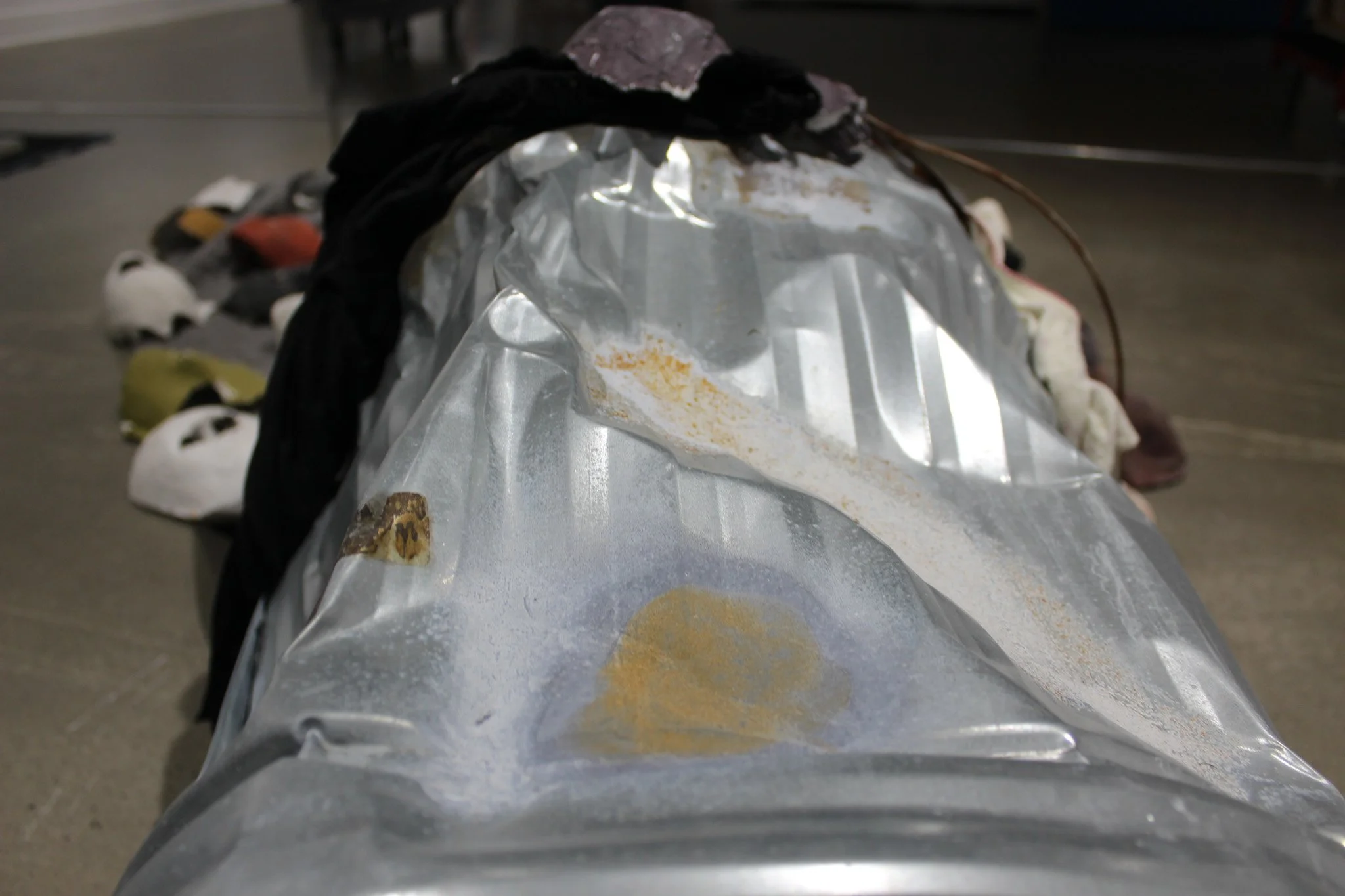 Reveal, 2025.
Metal trash can, plaster, resin, paint, clothes, blankets and boxes.
98 x 54 x 24 inches.