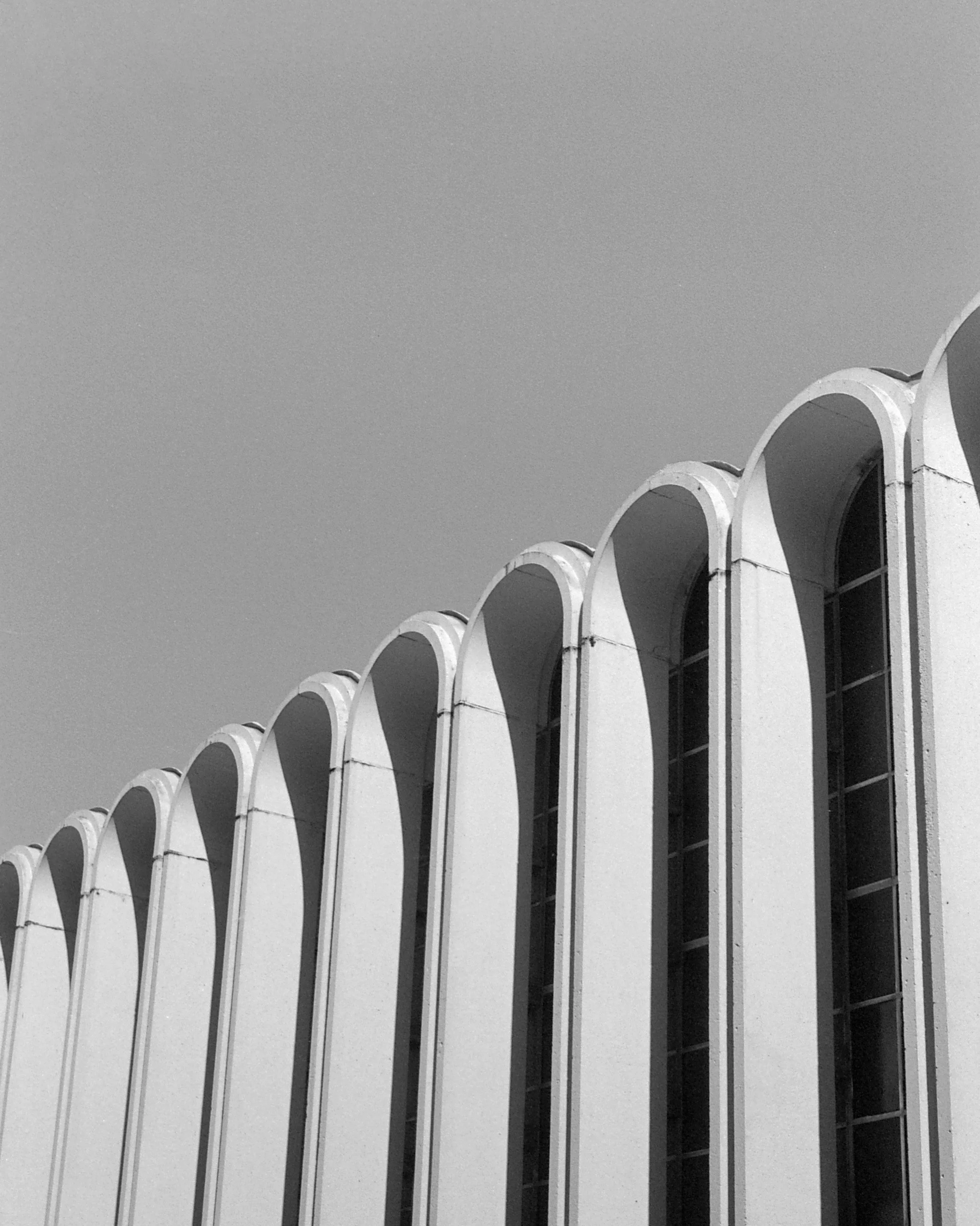 Black and white photo of high-rise building with a series of arched windows or openings along the top.