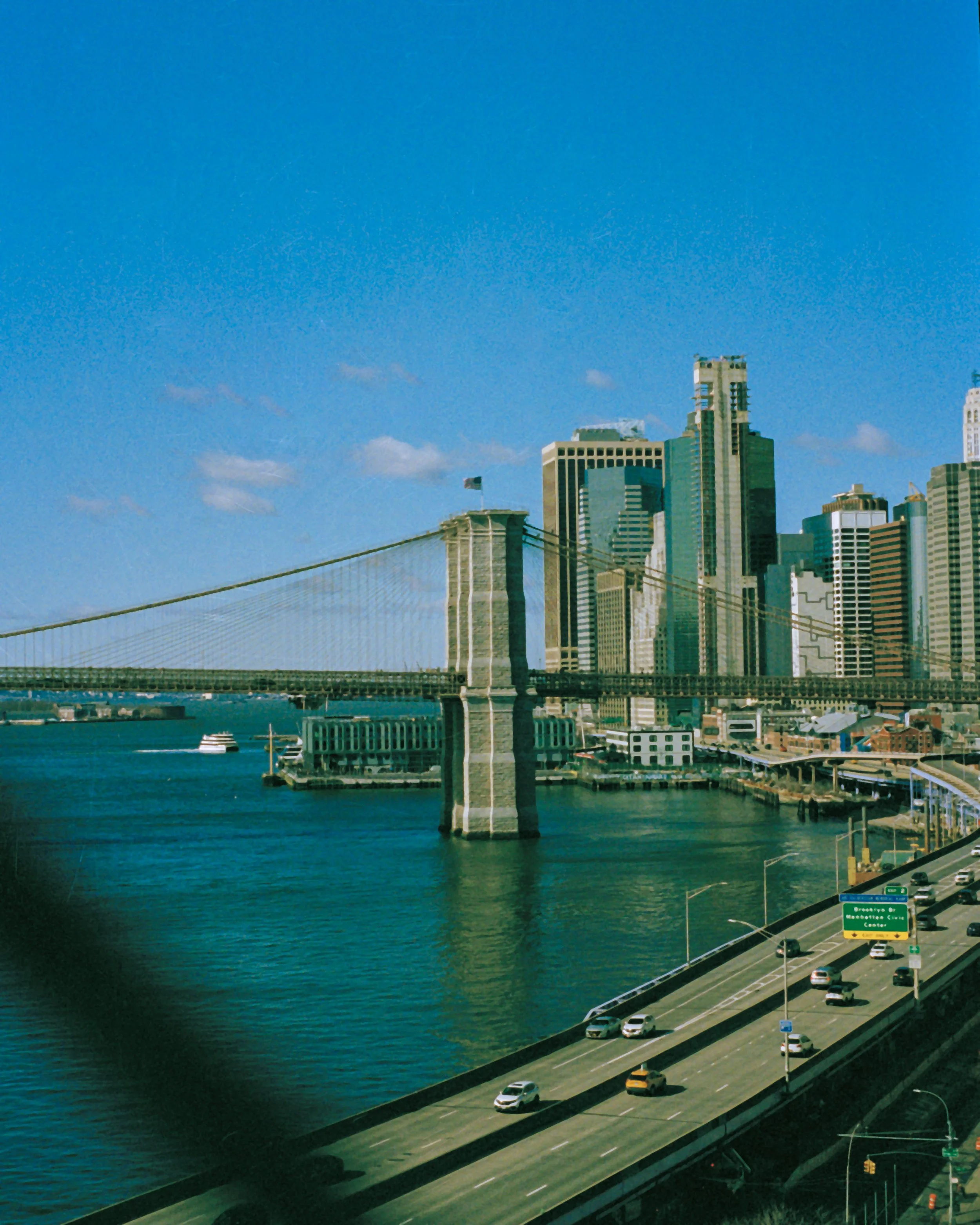 View of the Manhattan Bridge over the East River with the Manhattan skyline in the background on a clear day.