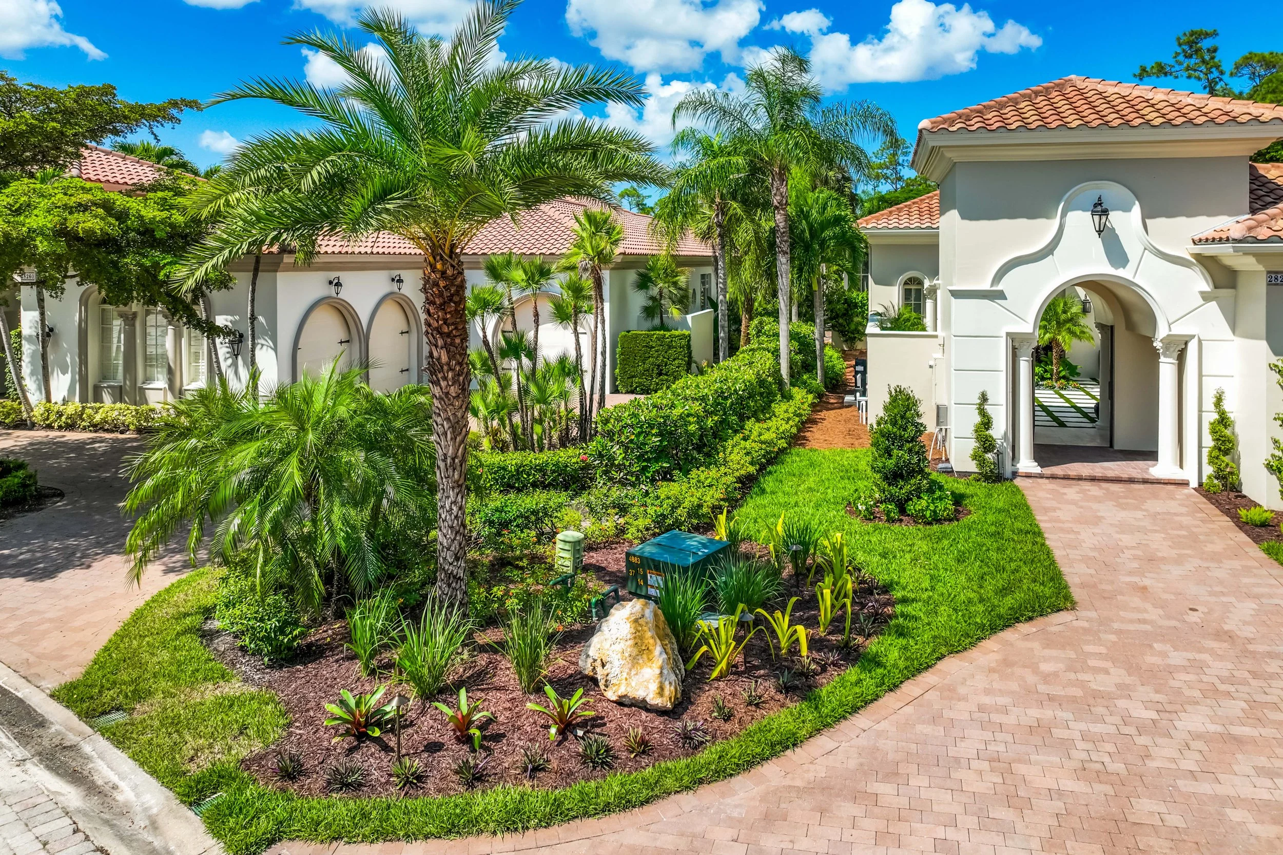 Refined landscape design with structured planting layout and large foxtail palm near driveway.