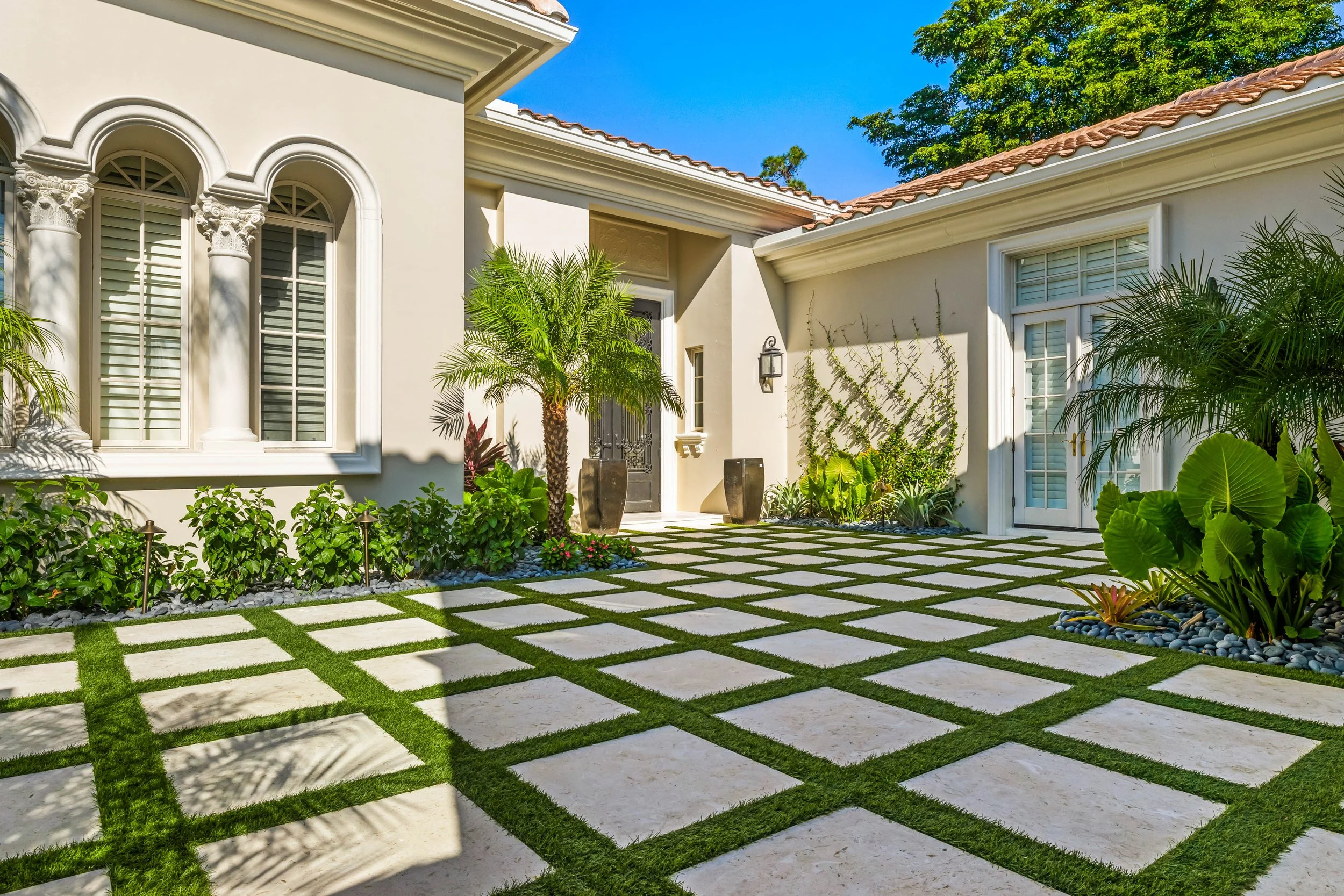 Grid-style turf and concrete driveway with clean geometric lines and foundation landscaping.