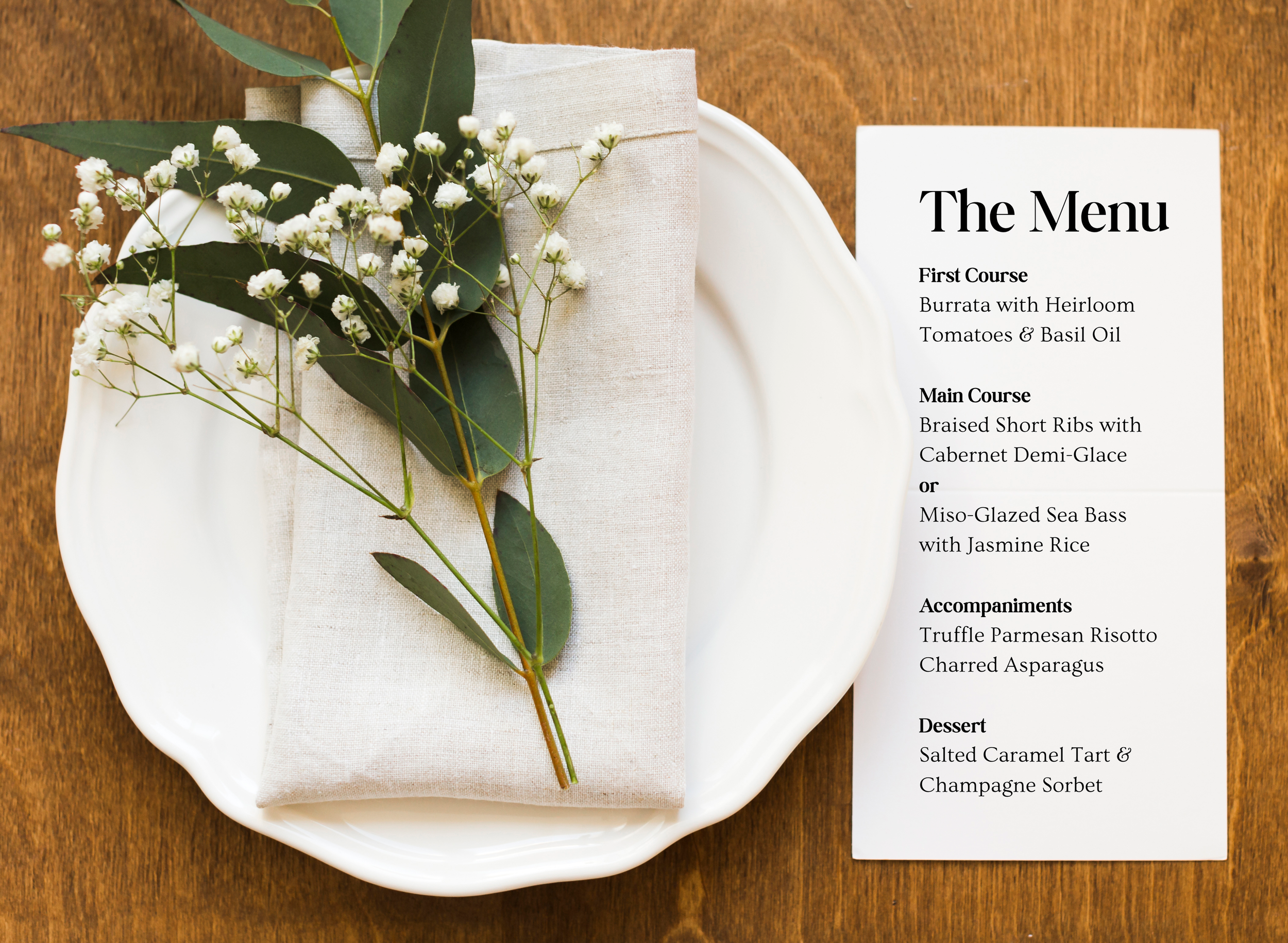 Elegant white plate with a beige napkin and greenery atop, placed on a wooden table, next to a printed menu listing a multi-course meal with gourmet dishes.