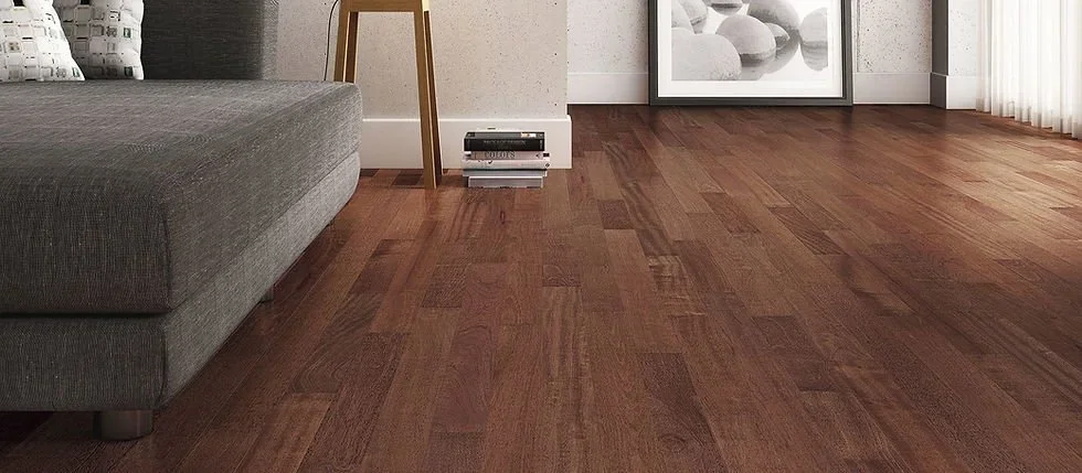 Living room with hardwood flooring, a gray sofa, a small side table, and framed artwork leaning against the wall