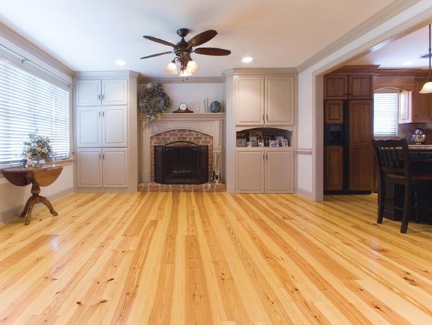 Living room with light hardwood floors, white built-in cabinets around the fireplace, and a ceiling fan.