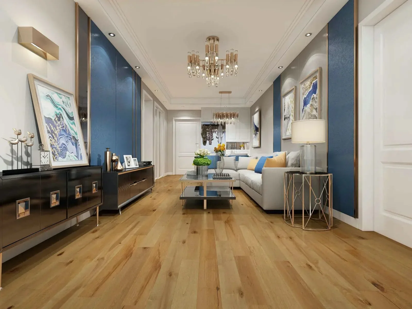 Living room with hardwood floors, a white couch with yellow and blue pillows, a gold side table with a lamp, modern artwork on the walls, a black console table, and two chandeliers hanging from the ceiling.