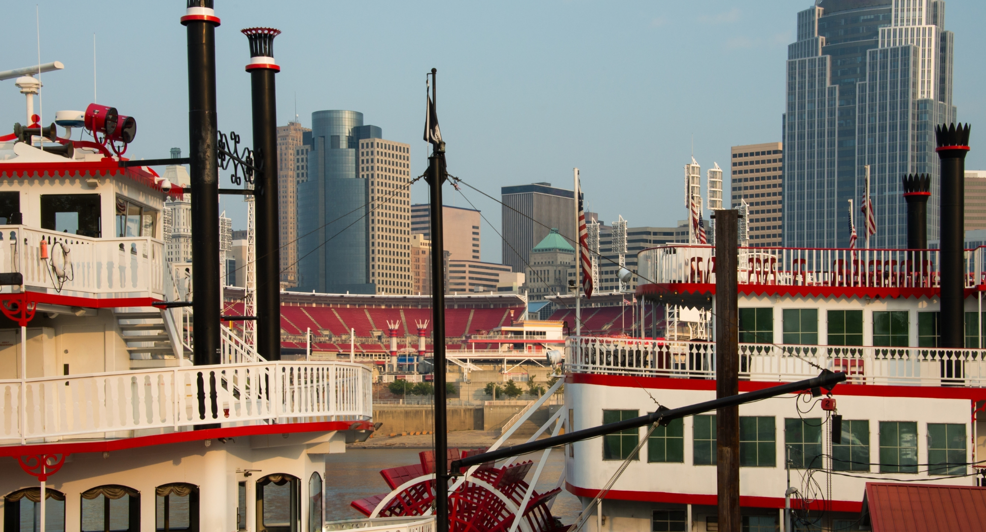 View of riverboats docked at a marina with a city skyline featuring tall skyscrapers in the background.