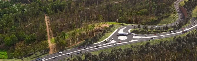 Aerial view of a curved highway surrounded by trees and a forested area.