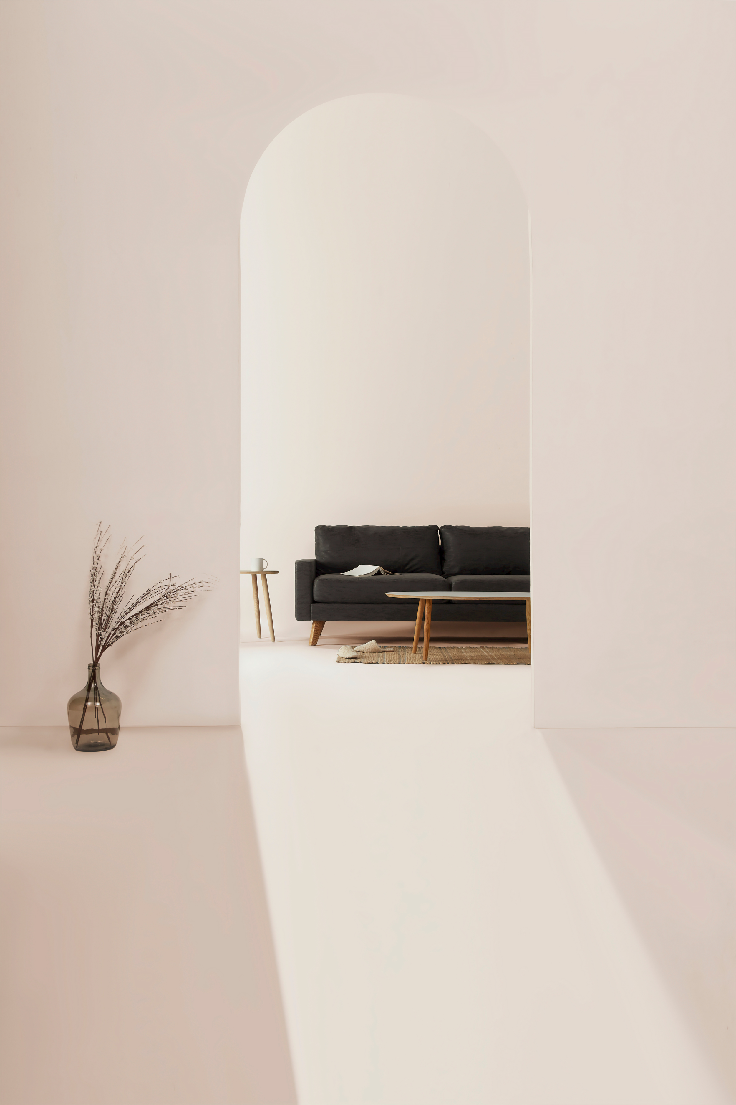 Minimalist living room with white walls, a black sofa, a small wooden side table, a rug, and dried plants in a glass vase.