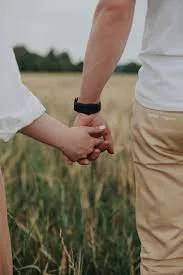 Two people holding hands in a field, representing couples therapy using Emotionally Focused Therapy (EFT) for connection and attachment healing.