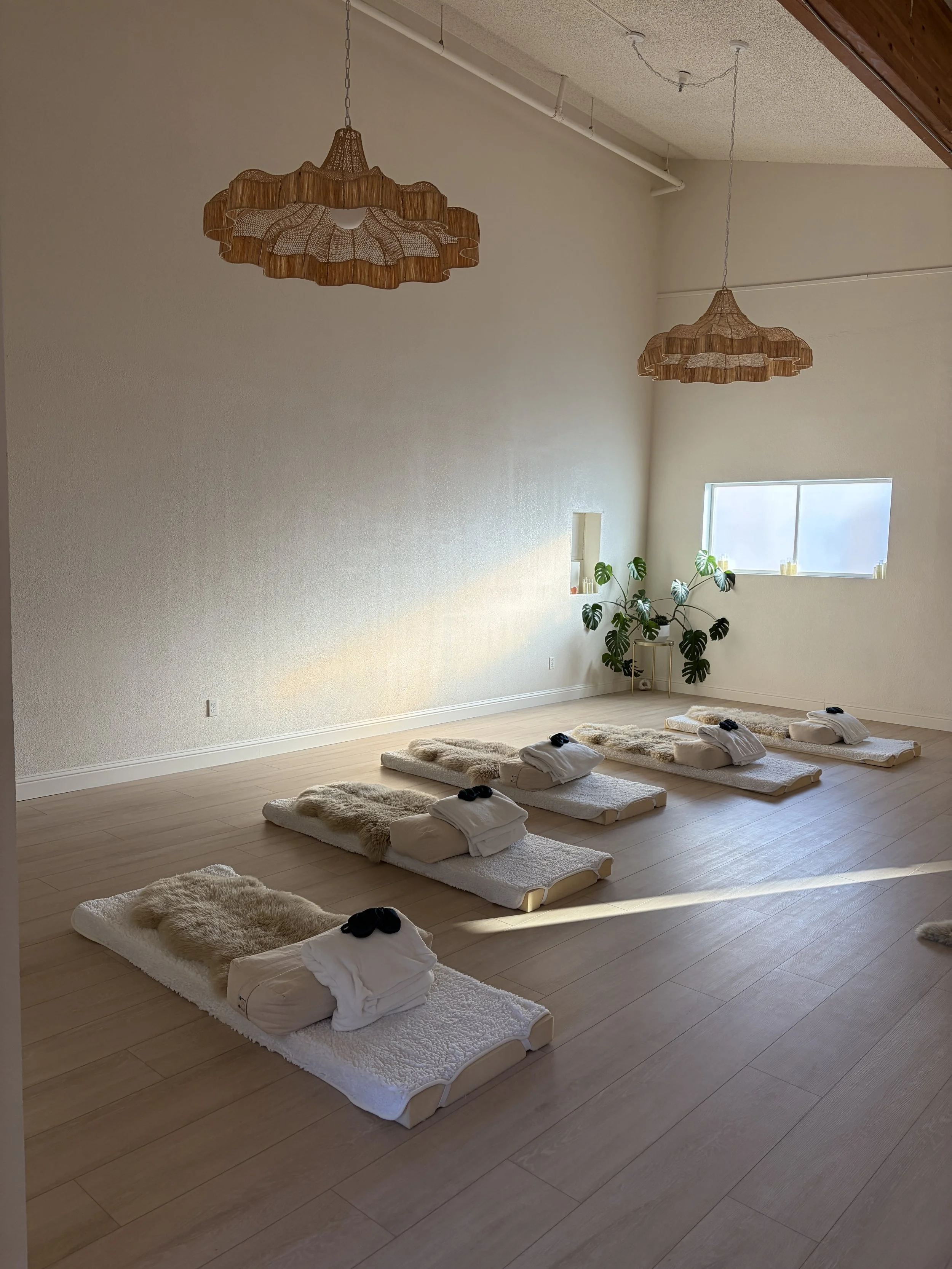 Bright wellness studio set up for a sound bath, meditation, or group healing session with floor mats, blankets, and pillows.